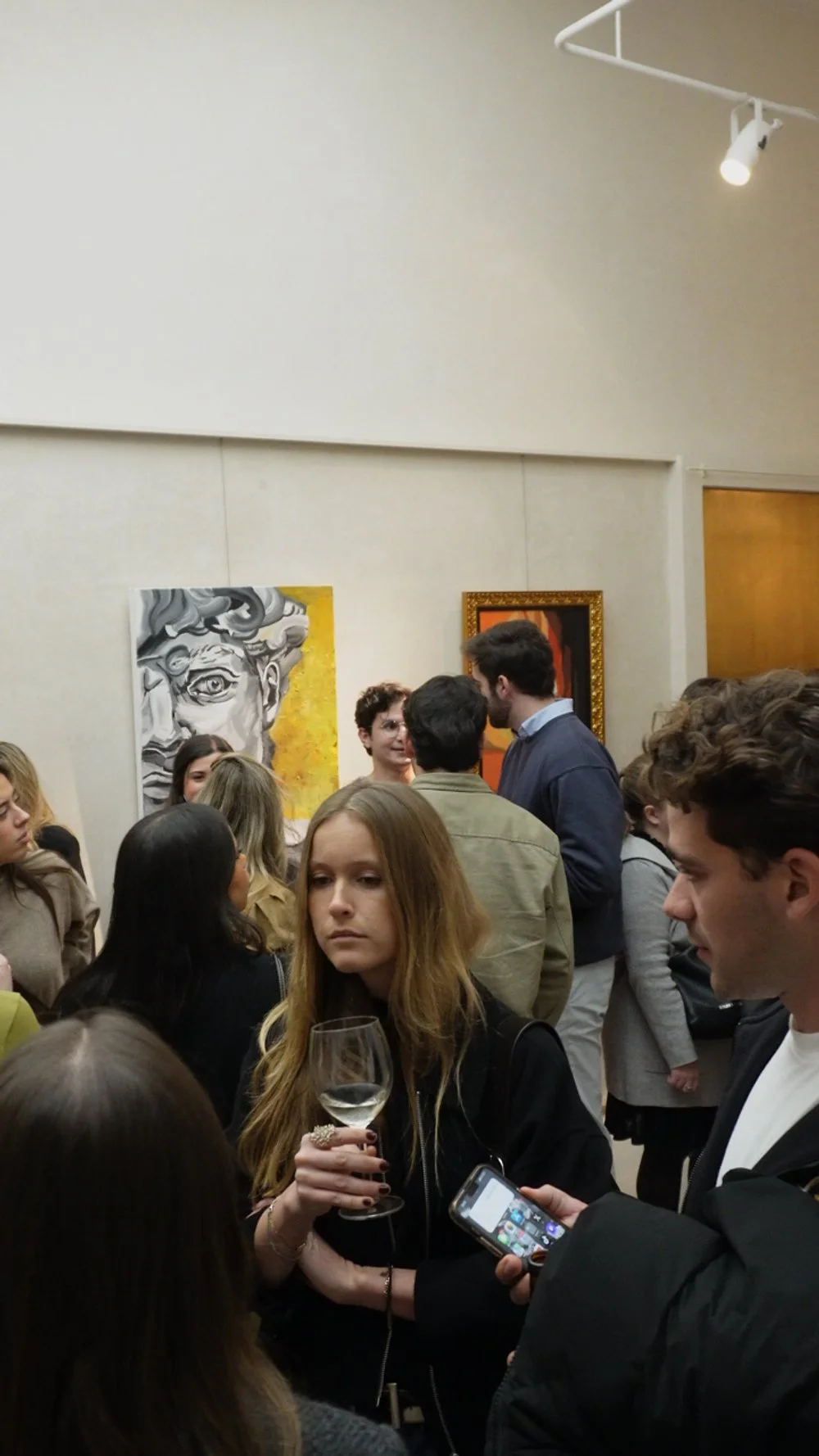 Personas en una exposición de arte, observando pinturas en la pared.