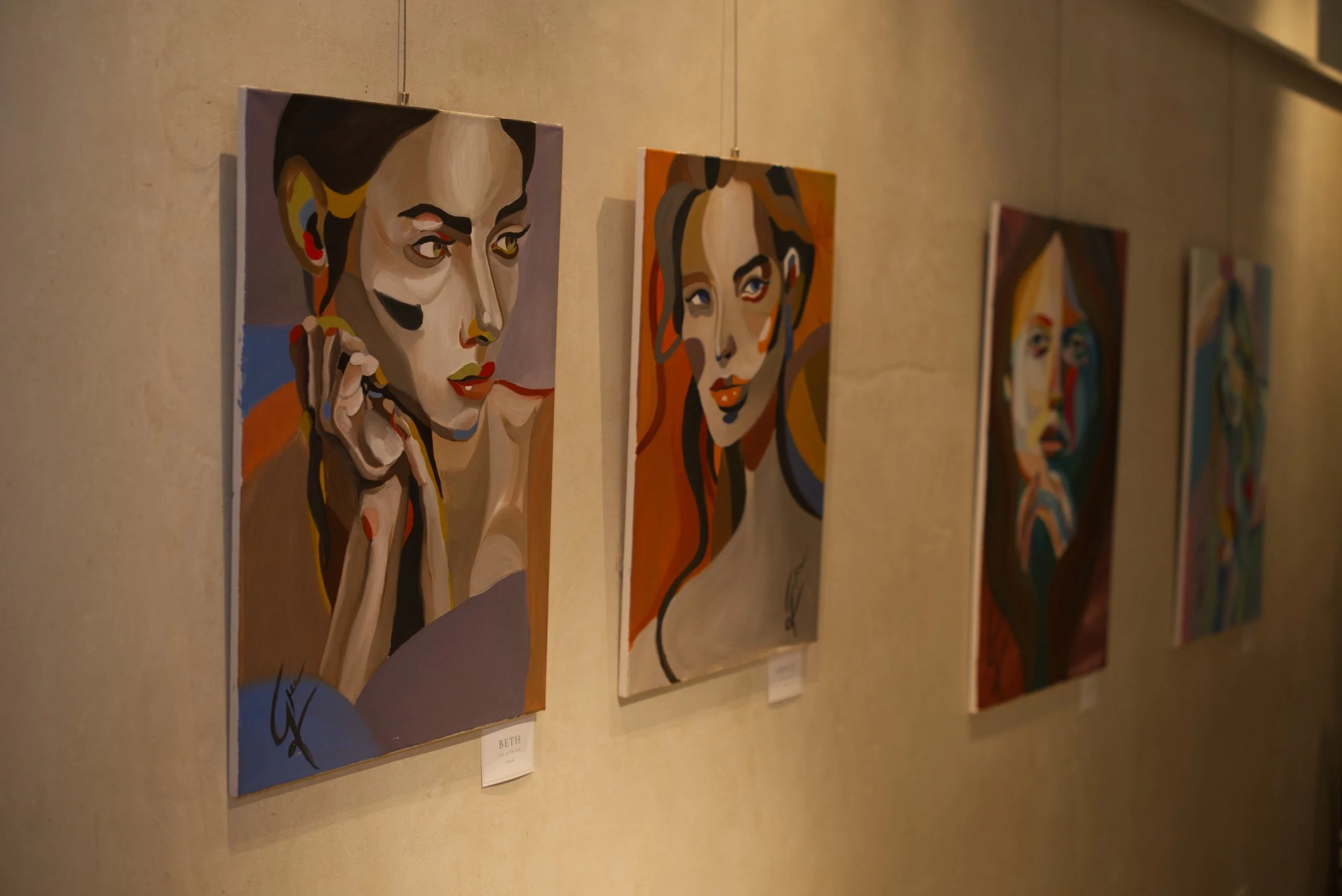 Serie de cuadros de estilo retrato en colores vibrantes en una galería.