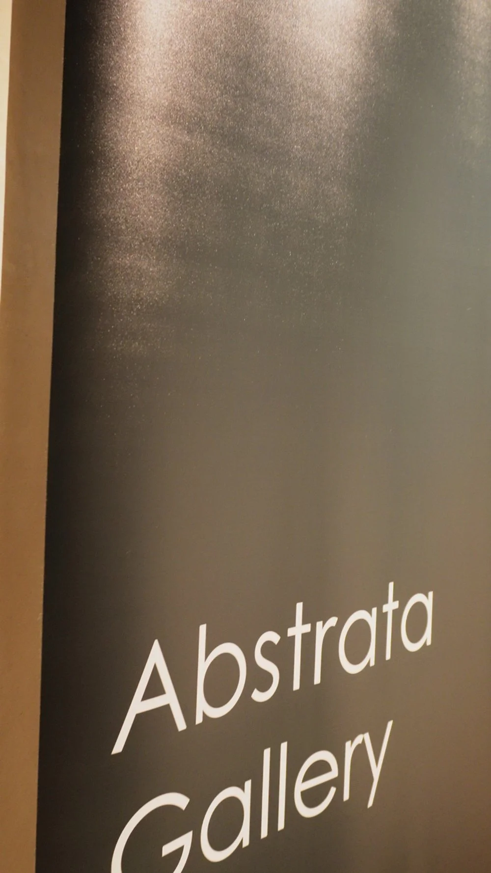 Cartel con fondo negro y texto en blanco que dice 'Abstrata Gallery' en letras grandes.