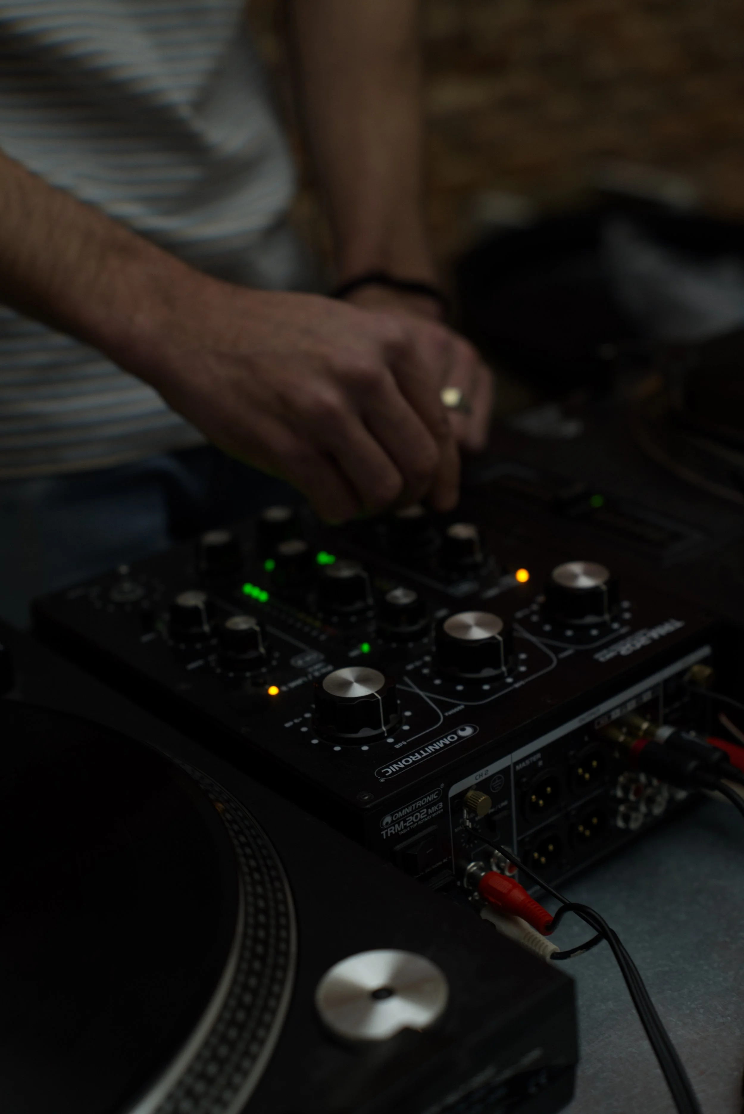 Persona usando un mezclador de música en un entorno oscuro.