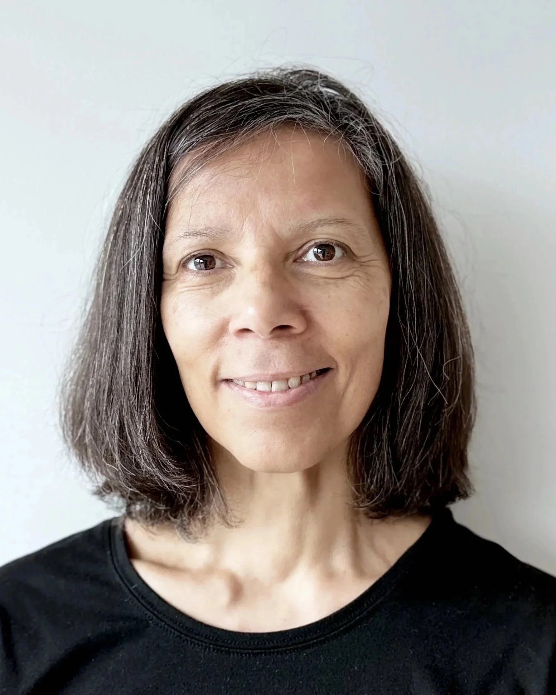 Lächelnde Frau sitzt in einem Raum mit Kunstwerken an der Wand.