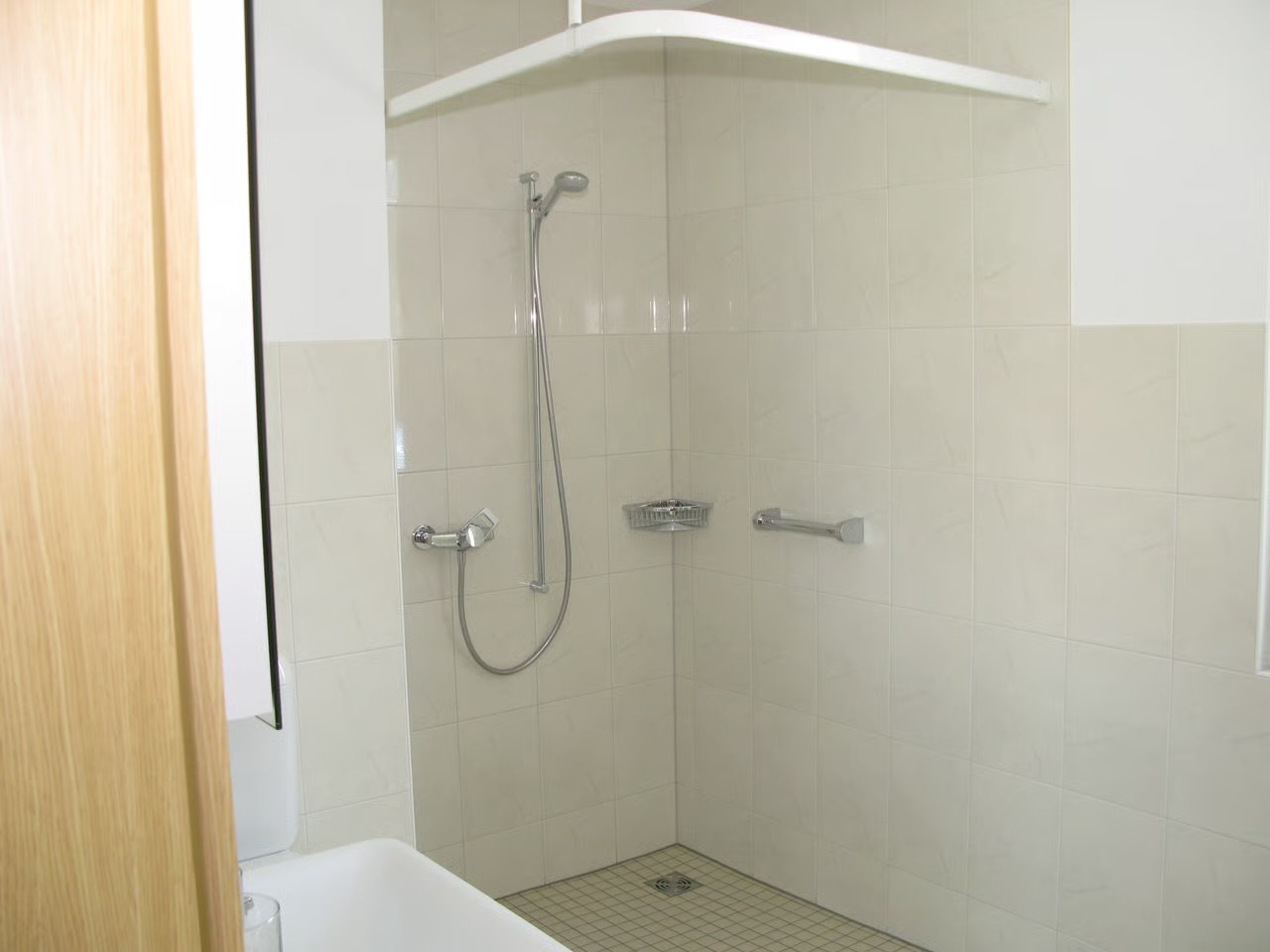 Badezimmer mit Dusche, Wasserhahn, Duschkopf, eine Ablage und eine Handlauf