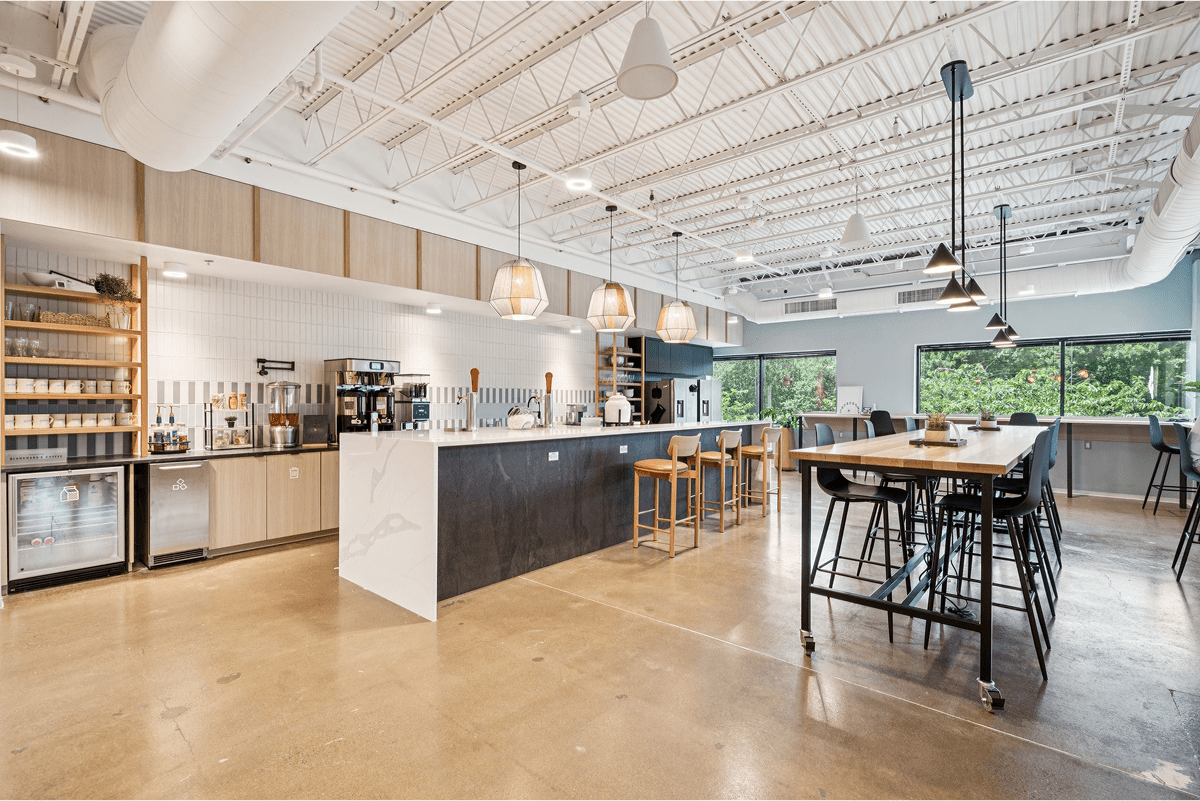Bright and open coworking space with kitchen, hightop tables, hanging pendant lights
