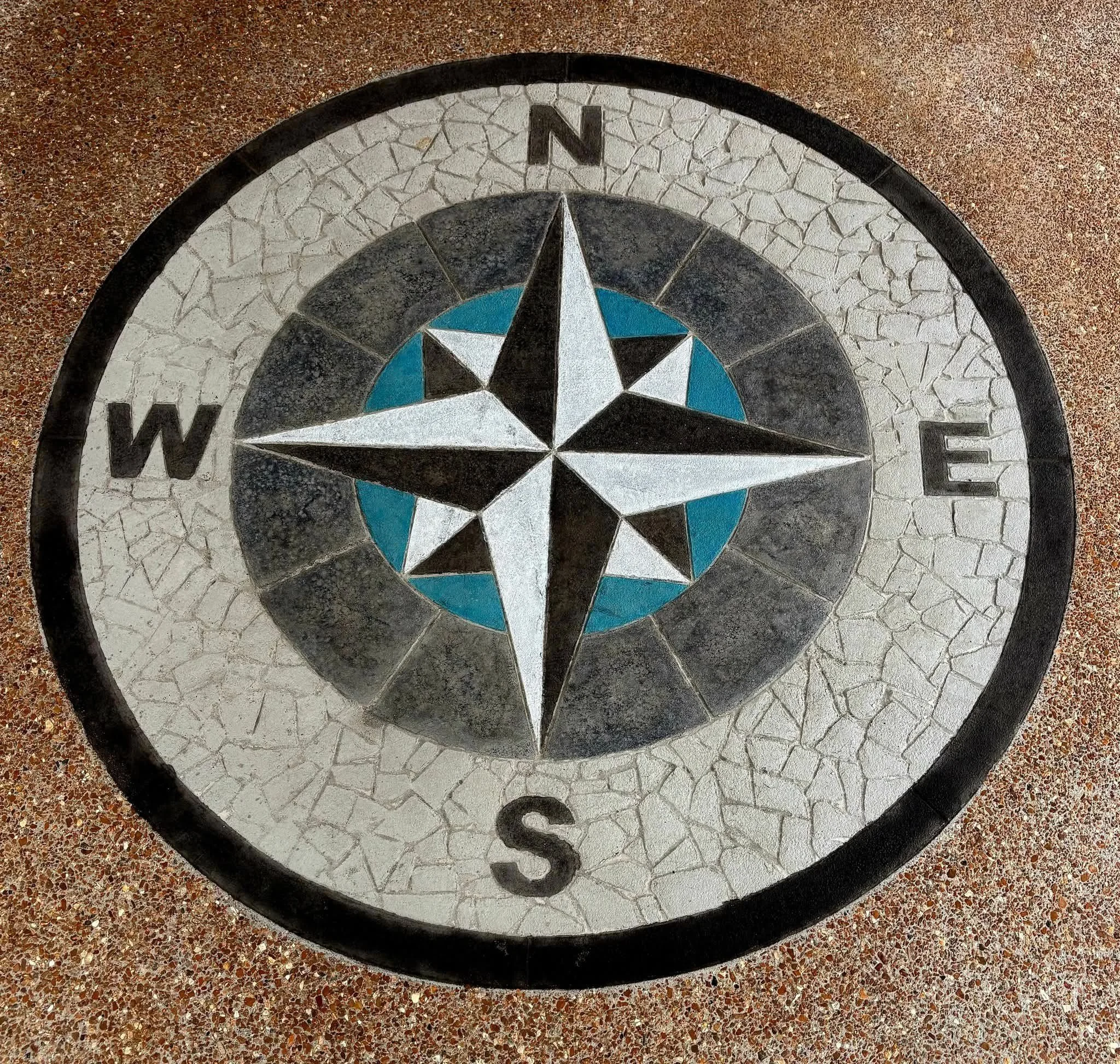 Decorative compass rose mosaic on ground with North, South, East, West labels