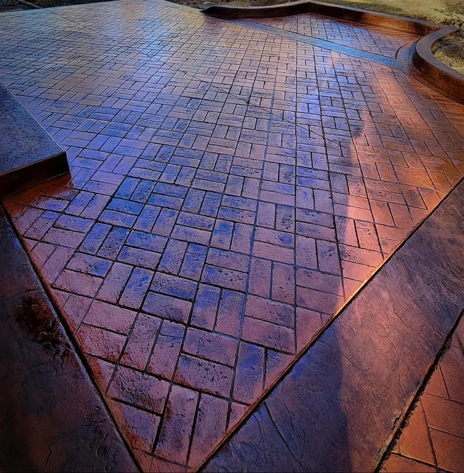 Wet brick pathway with curved edges and steps on the side, reflecting sunlight.