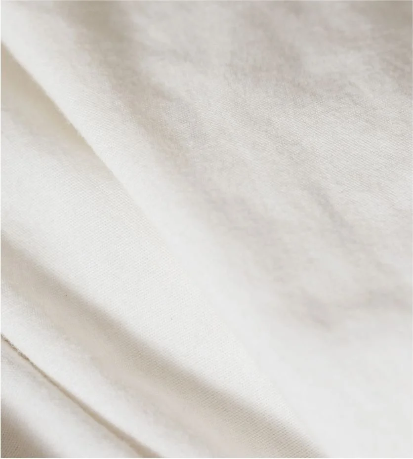 Close-up of smooth, off-white fabric with a subtle texture and folds.