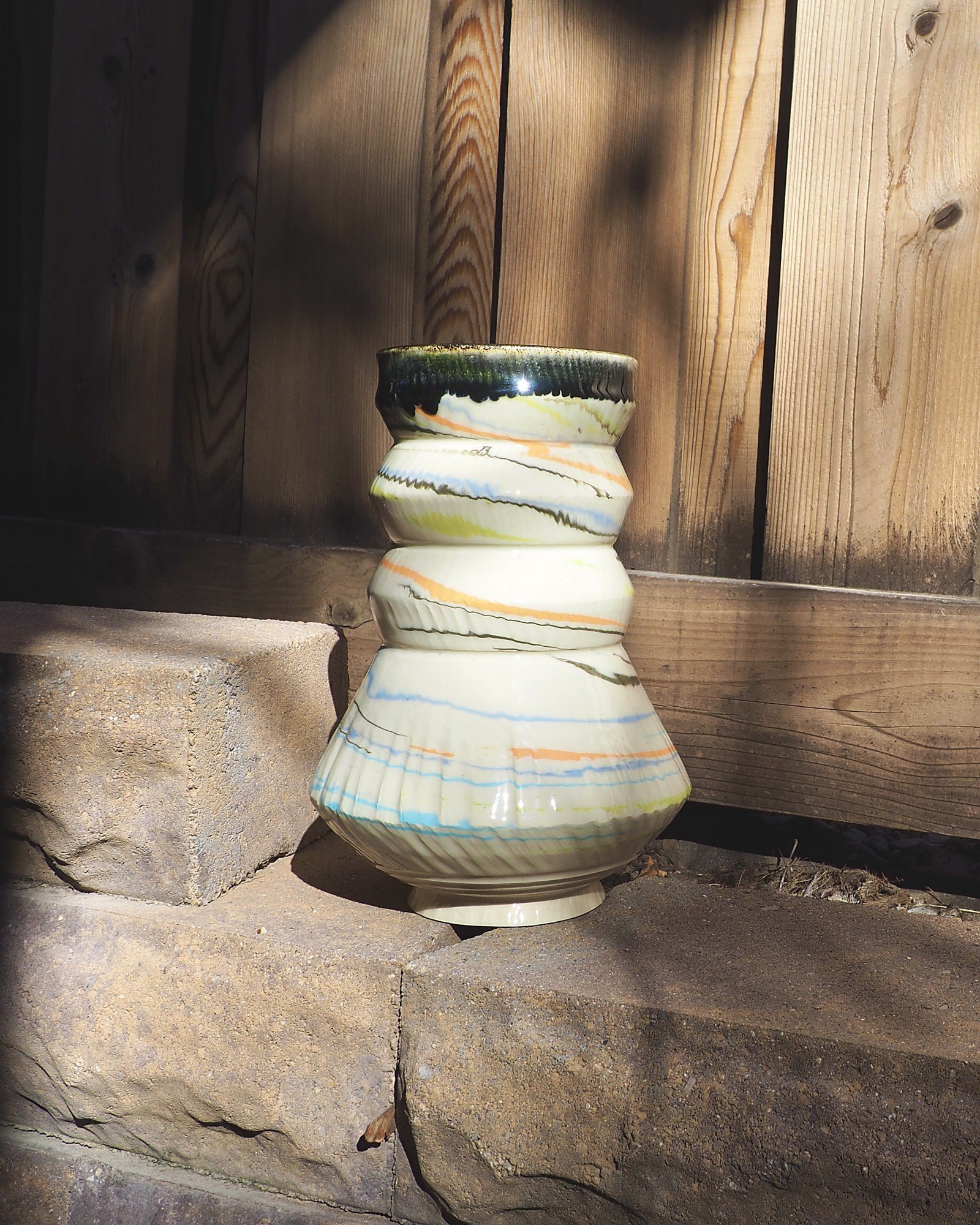 Wide view of the Marbled Swirl Tower vase on stone blocks