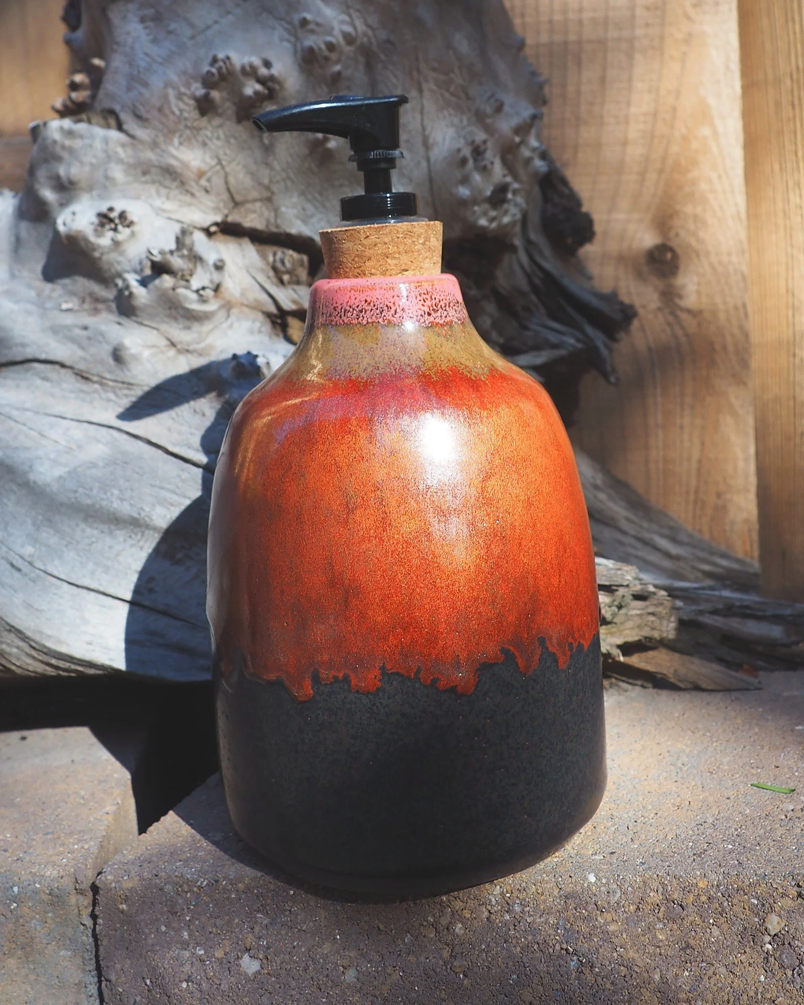 Lava Lather, a handmade ceramic soap dispenser with molten red-orange drip glaze over matte black and a cork-set pump