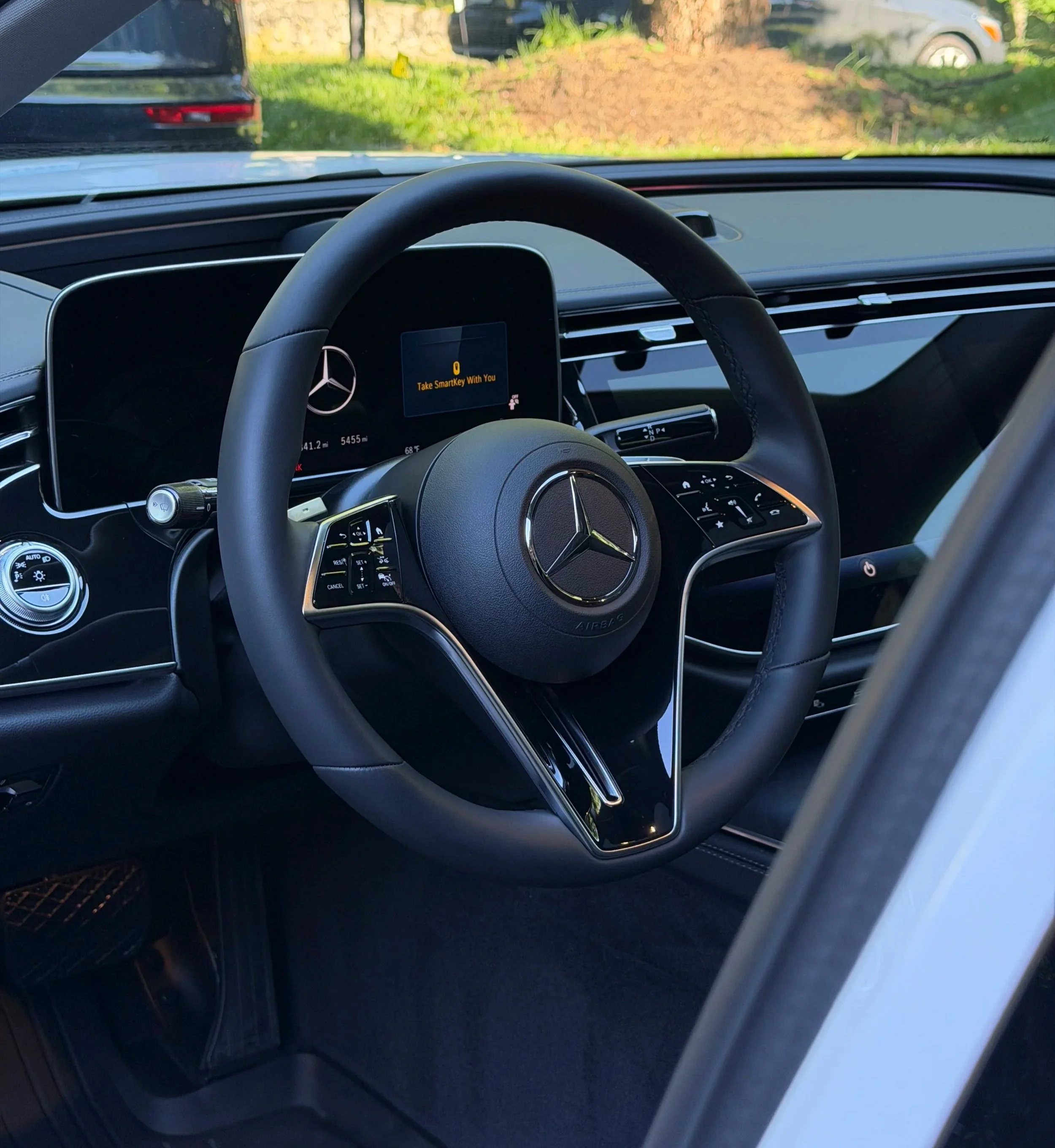 Inside the front of a Mercedes-Benz vehicle, showing the steering wheel and digital dashboard. The dashboard displays a message saying 'Take SmartKey With You' and the odometer reading 41.2 miles.