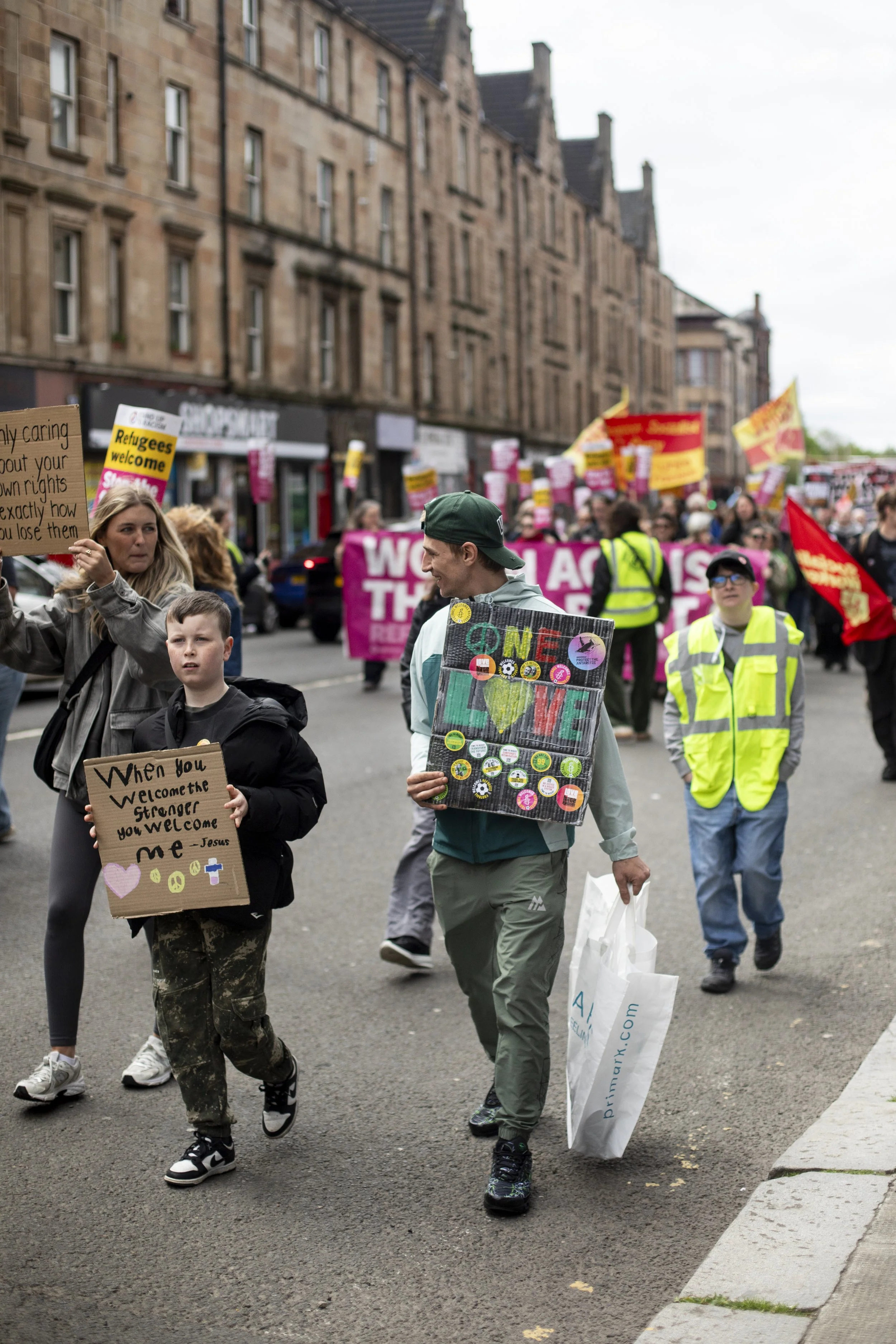 At a Stand Up To Racism protest in Glasgow on 9 May 2026, a man holds a sign reading “One Love” during a demonstration held after the Scottish Parliament elections.