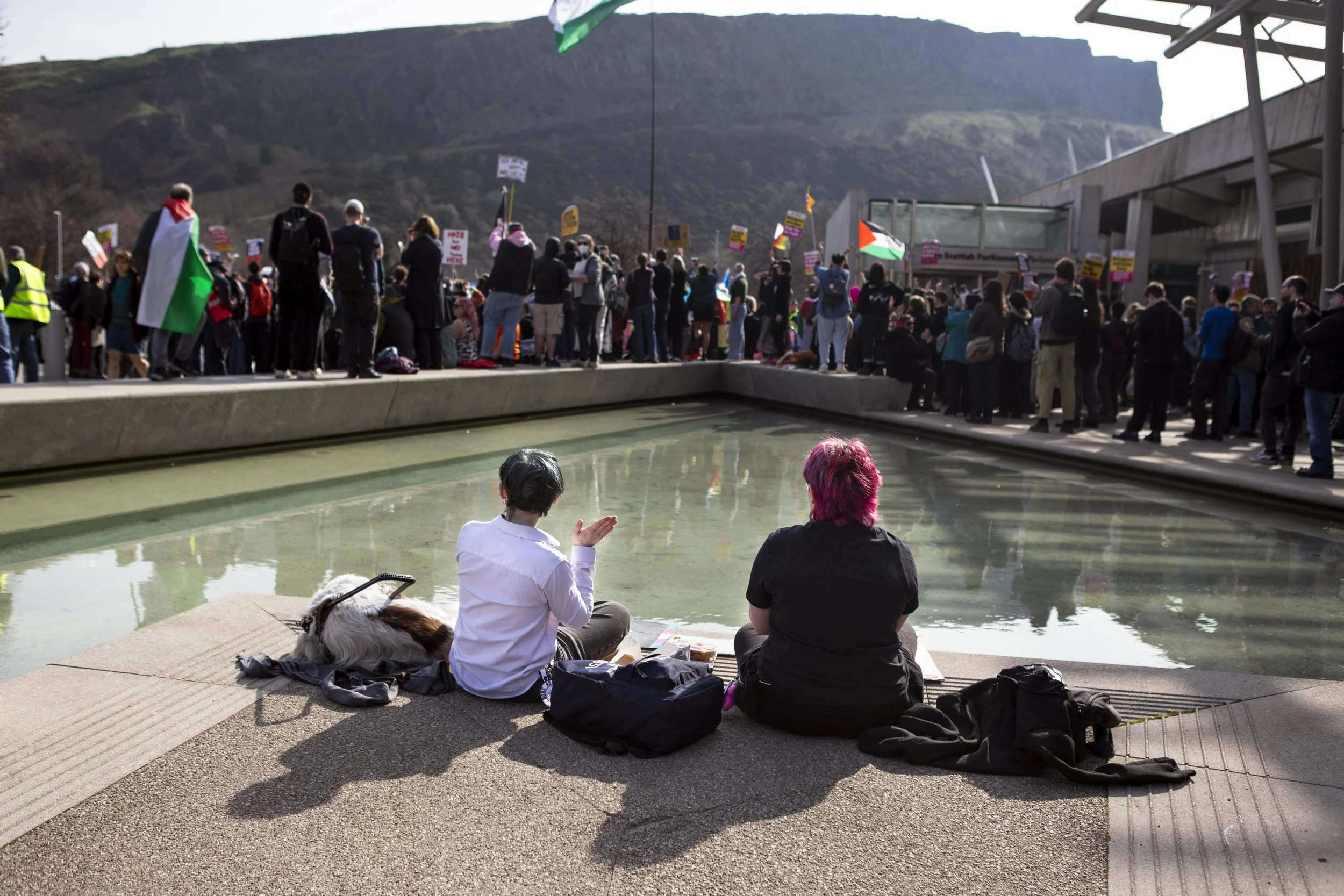 A mother, her son and their dog sit together eating lunch and cheering on the “Stand Up to Racism” protesters outside of Holyrood nearby during clashes between opposing groups.