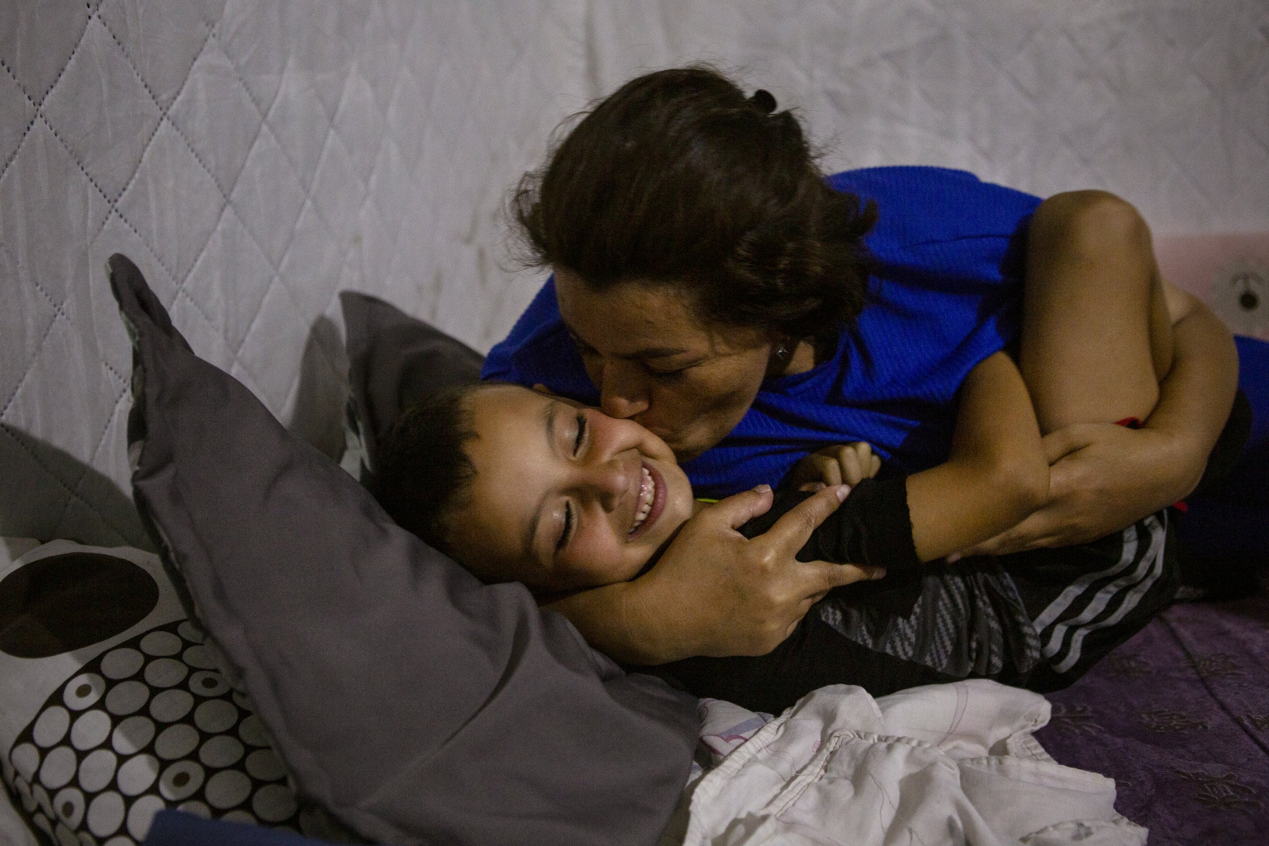 Fatme kisses her son Adam before they sleep in their tent in Biel.
