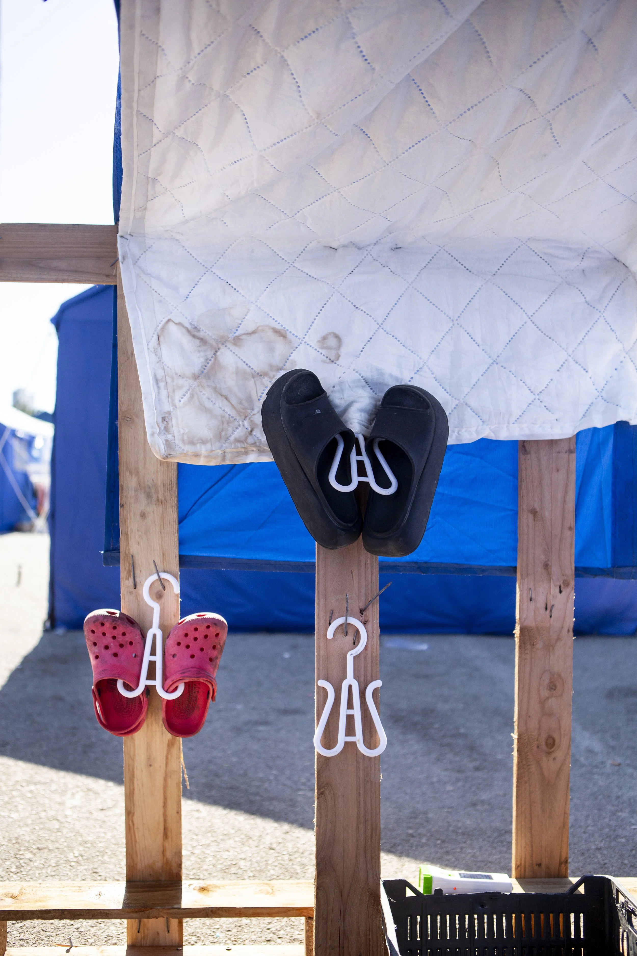 Jamal hangs up his family's shoes outside fo their tent.
