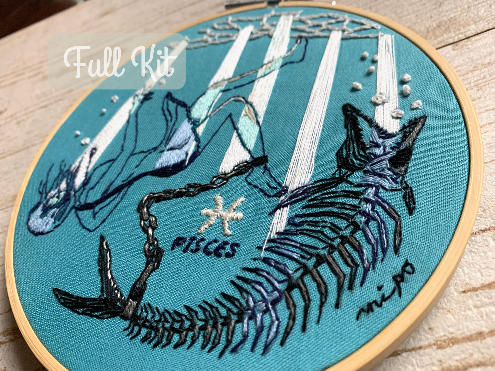 Finished Pisces embroidery design showing a girl and fish skeleton chained together underwater with light shining from above.