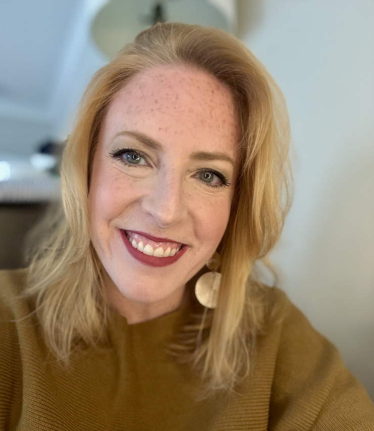 Close-up of a Jenny Liebel, wearing a brown top and a large circular earring, in an indoor setting.