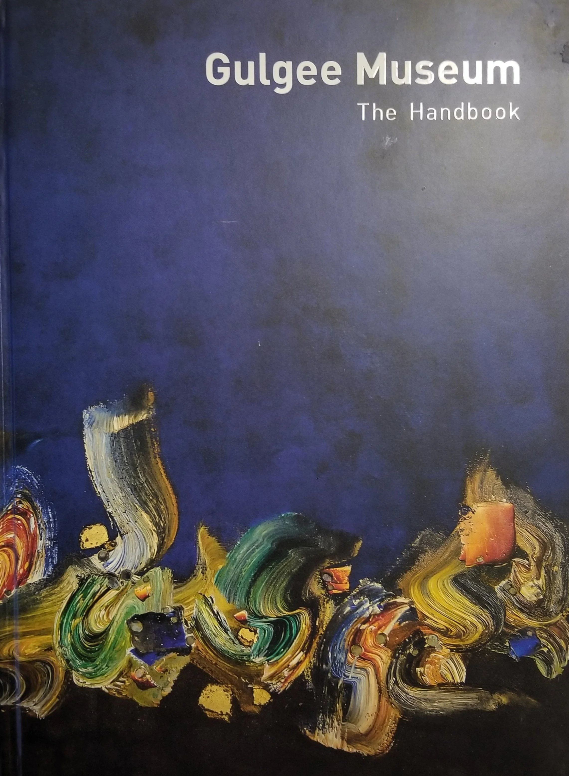 Cover of the Gulgee Museum Handbook with an abstract swirl of colorful paint strokes at the bottom, on a dark background.