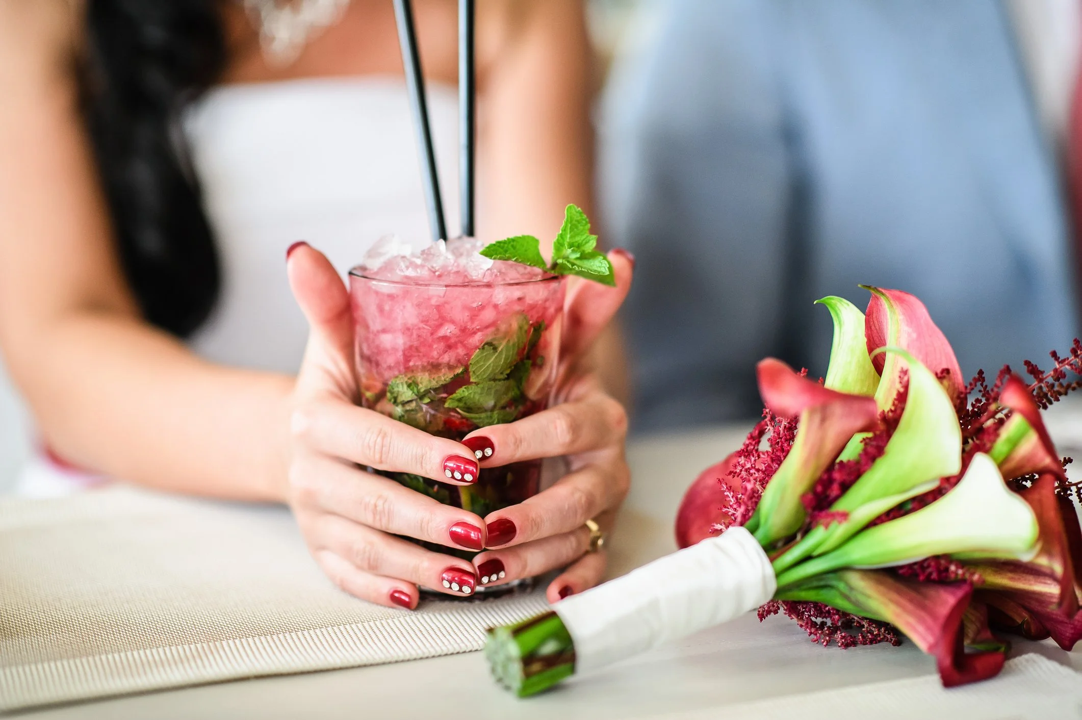 Close-up of a bride posing with a garden-to-glass cocktail with fresh mint garnish at a luxury wedding mobile bar.