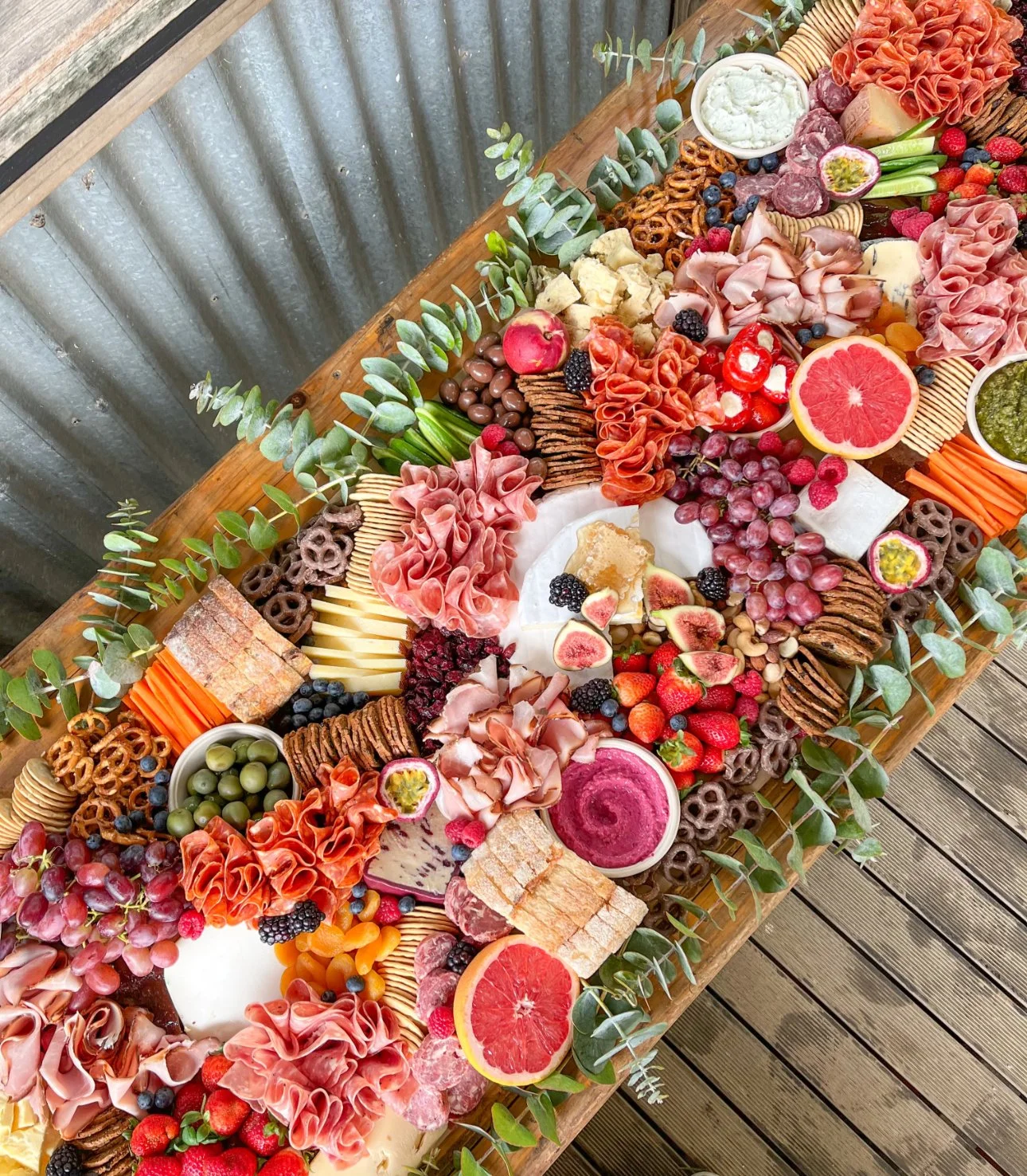 Bright and colorful Charcuterie Grazing Table with artisan cheeses, cured meats, fresh fruits, local cheeses, herb and floral garnishes. 