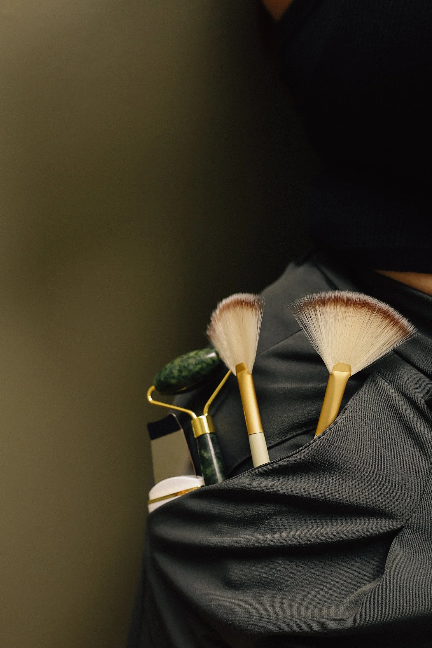 Makeup artist's pocket filled with makeup brushes, a roller, and a small container.