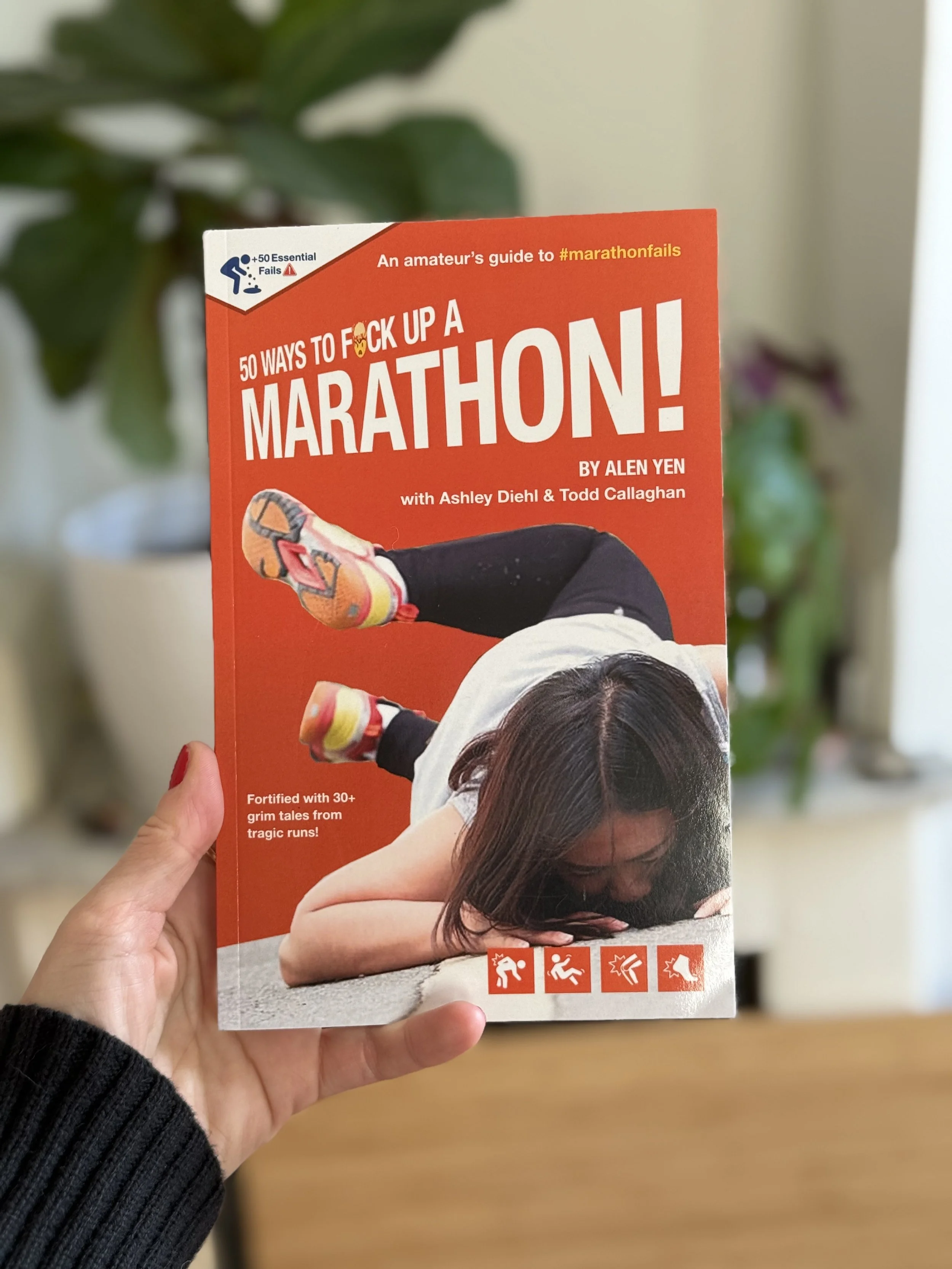 Book titled '50 Ways to F*ck Up a Marathon!' by Alen Yen, with Ashley Diehl & Todd Callaghan, featuring a woman lying on the ground with a marathon runner's pose and icons of marathon failures at the bottom.