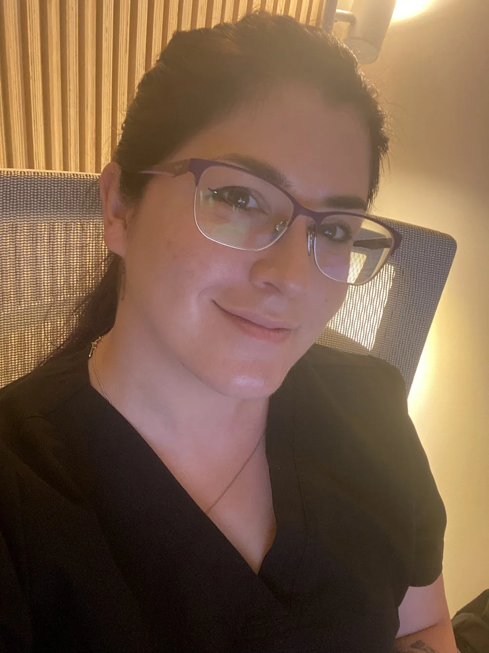 Close-up of woman with purple hair, glasses, and smiling