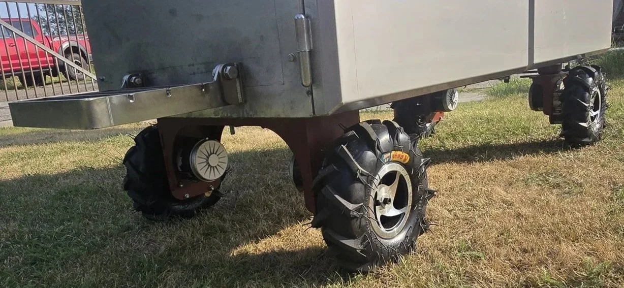 Een vierwielig voertuig met off-road banden, gebruikt voor rijden op ruw terrein, en een metalen laadplatform erboven.
