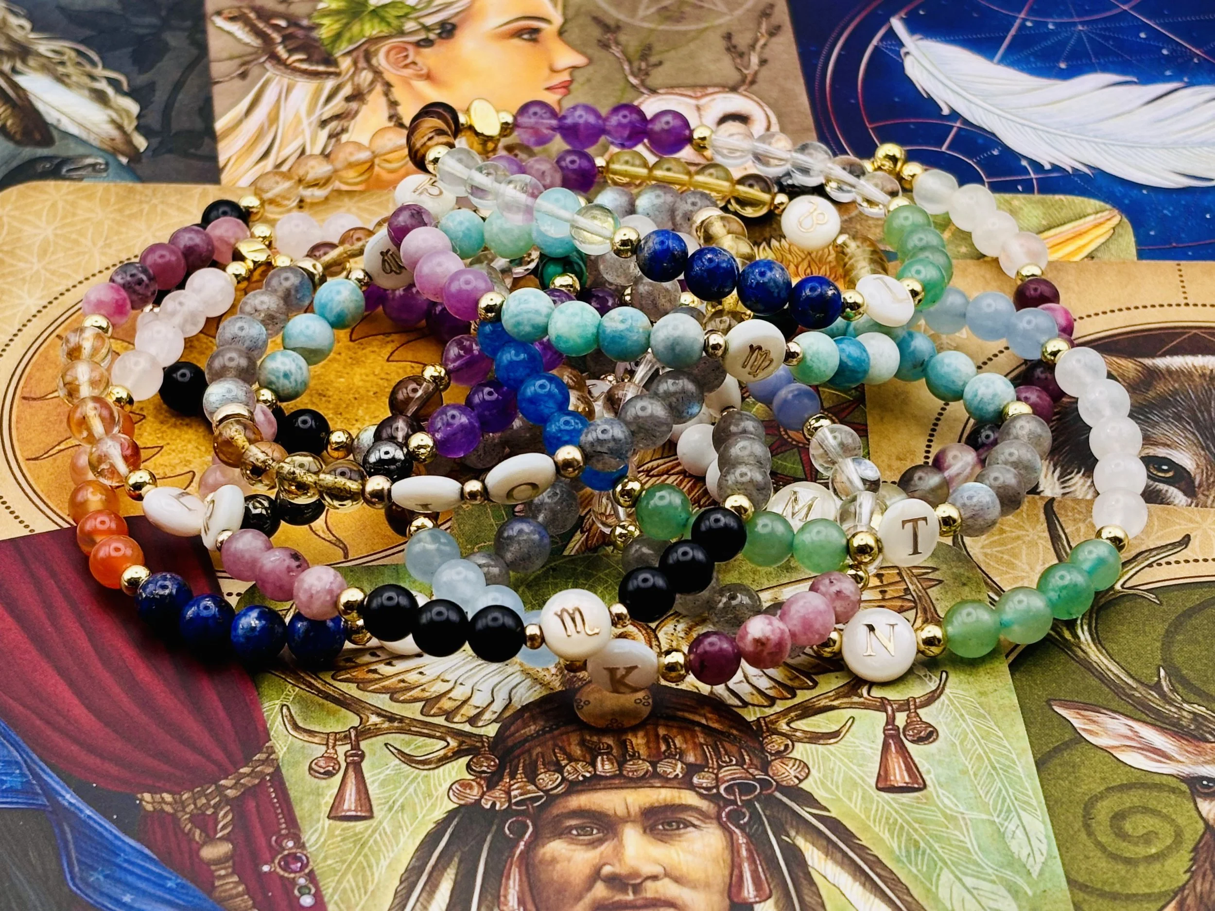 Colorful beaded jewelry necklaces placed on a vibrant card featuring Indian artwork of a woman with a headdress, feathers, and intricate details.