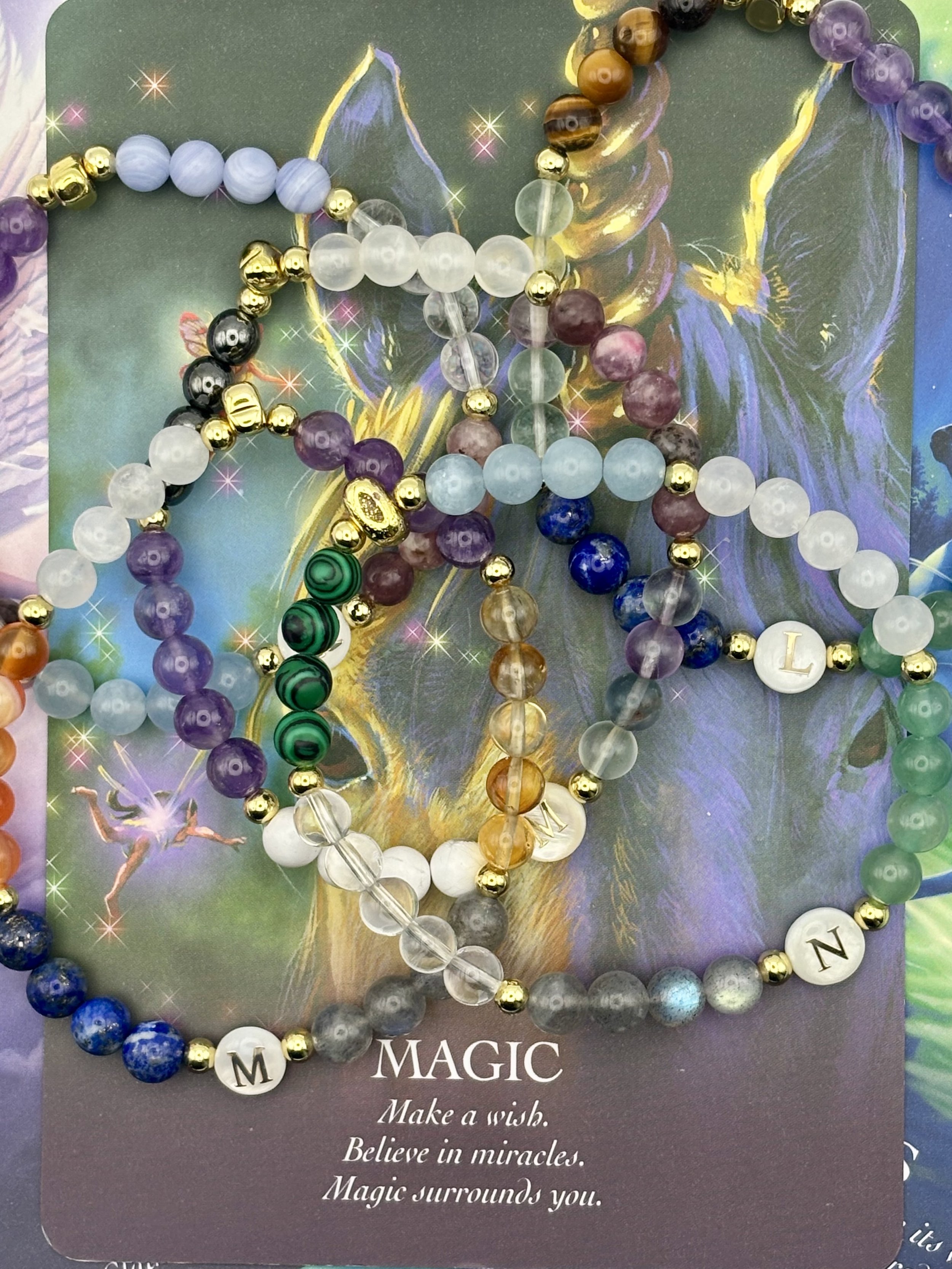 Various beaded bracelets with colorful and metallic beads, placed on a card that reads 'MAGIC' with inspirational phrases.