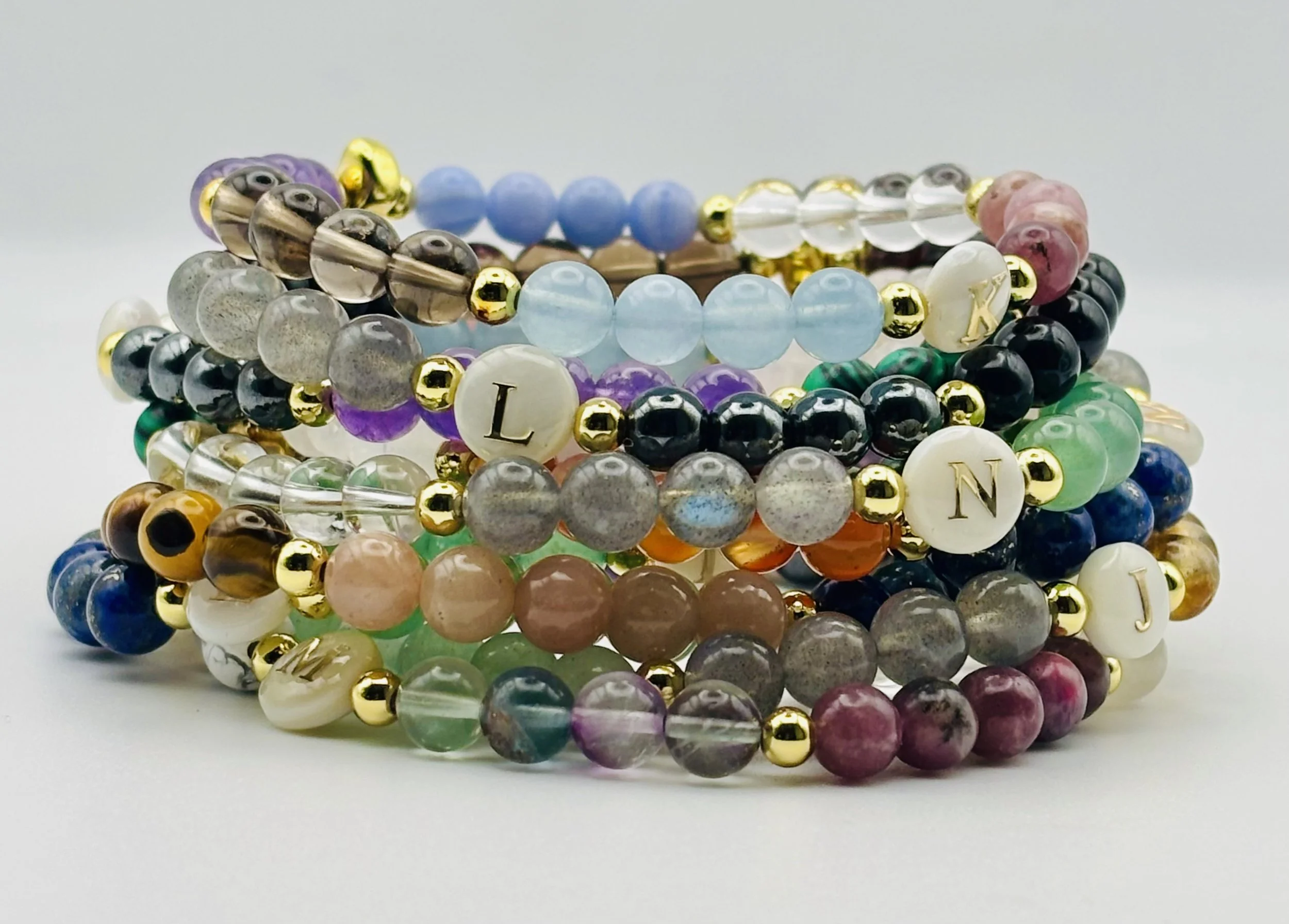 Colorful beaded bracelets with various colors and metallic accents stacked on a plain background.