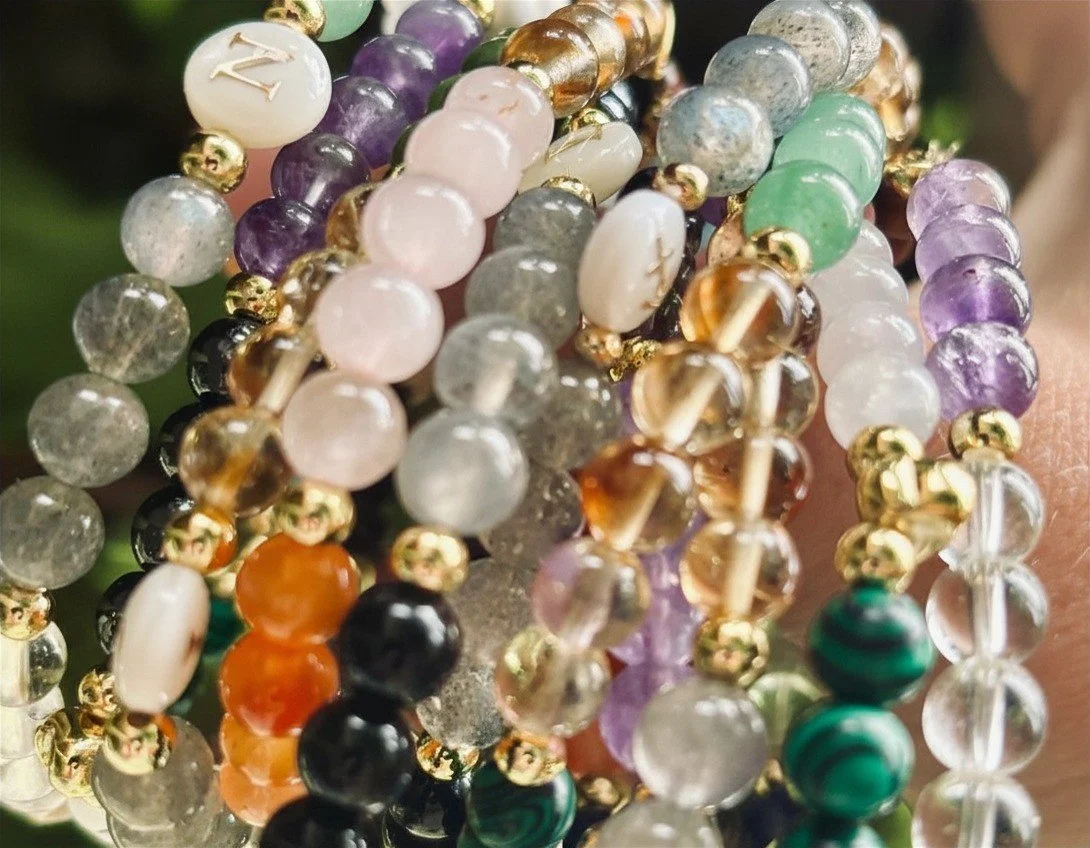 Close-up of multiple colourful crystal bracelets with gold accents.
