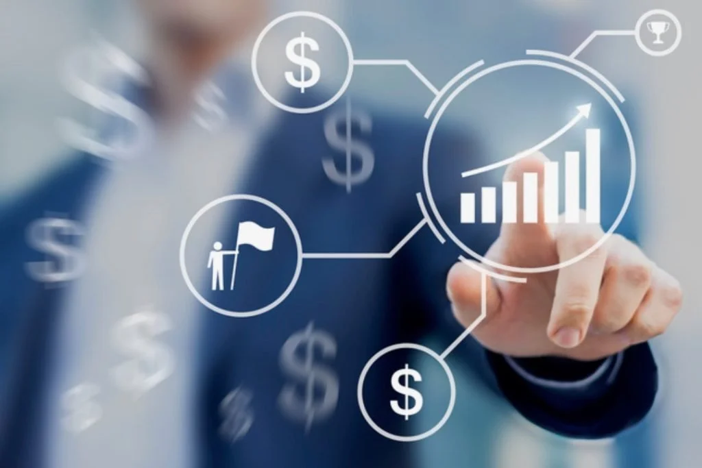 A person in a business suit interacts with a digital financial chart and icons, including dollar signs, a flag, and a trophy, representing financial growth and success.