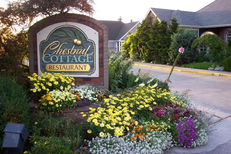 Sign for Chestnut Cottage Restaurant surrounded by colorful flowers