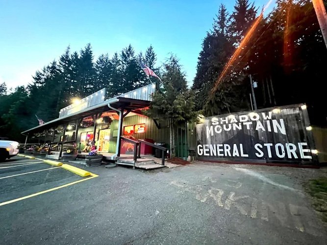 Shadow Mountain General Store in a forested area with a parking lot in front.