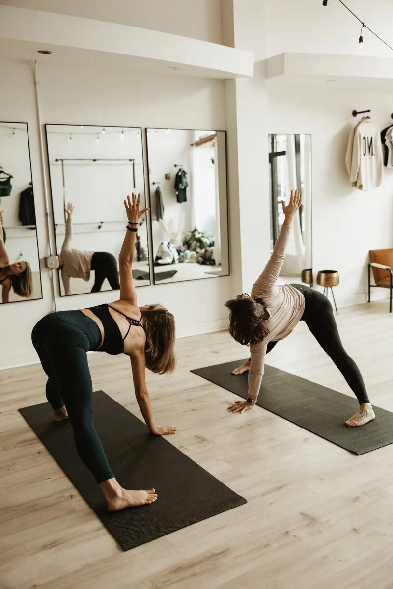 People working out inside ONYX Studios, with neutral tones decor and black yoga mats.