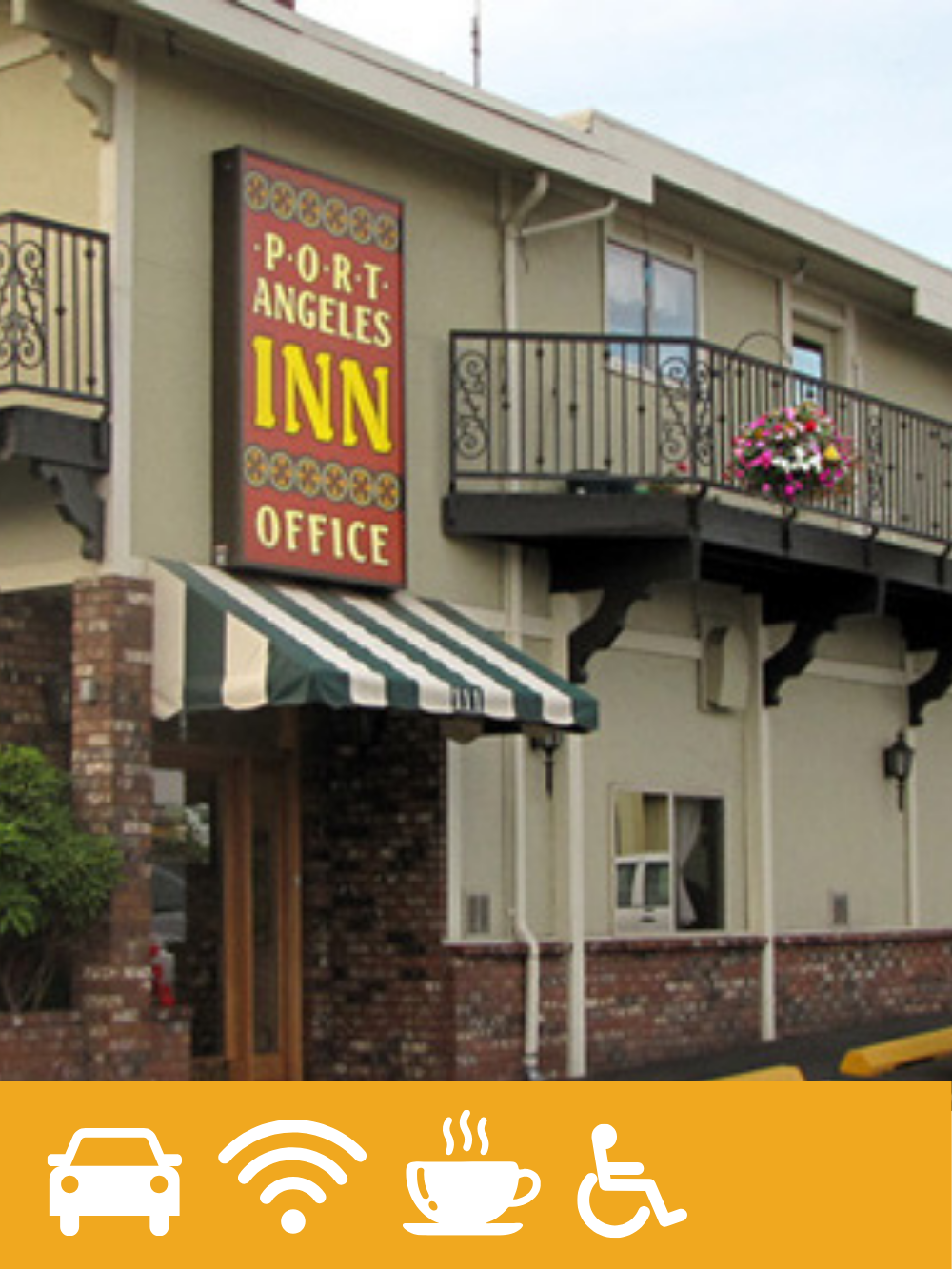 Exterior of a small building with a sign that reads 'Port Angeles Inn Office'. The building has a balcony with pink flowers, brick and stucco walls, and a green and white striped awning over the entrance.