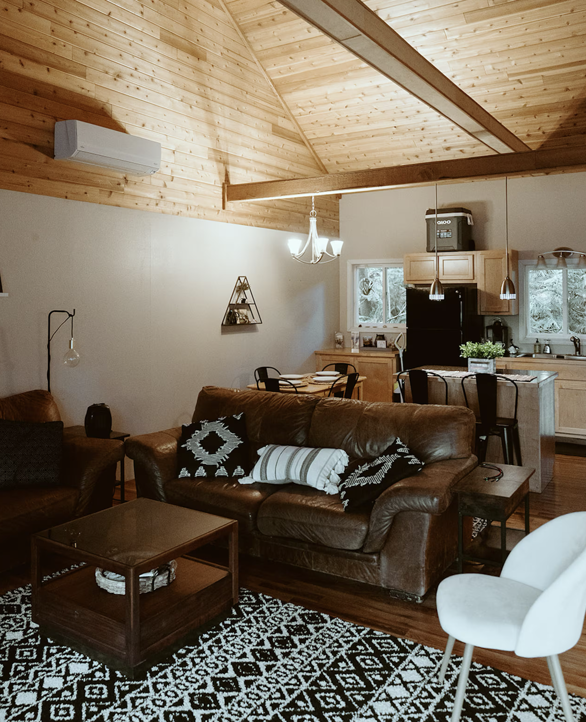 Interior of a cozy cabin airbnb in the Olympic National Park area, featuring pine wooden cielings, a leather couch, and modern decor.