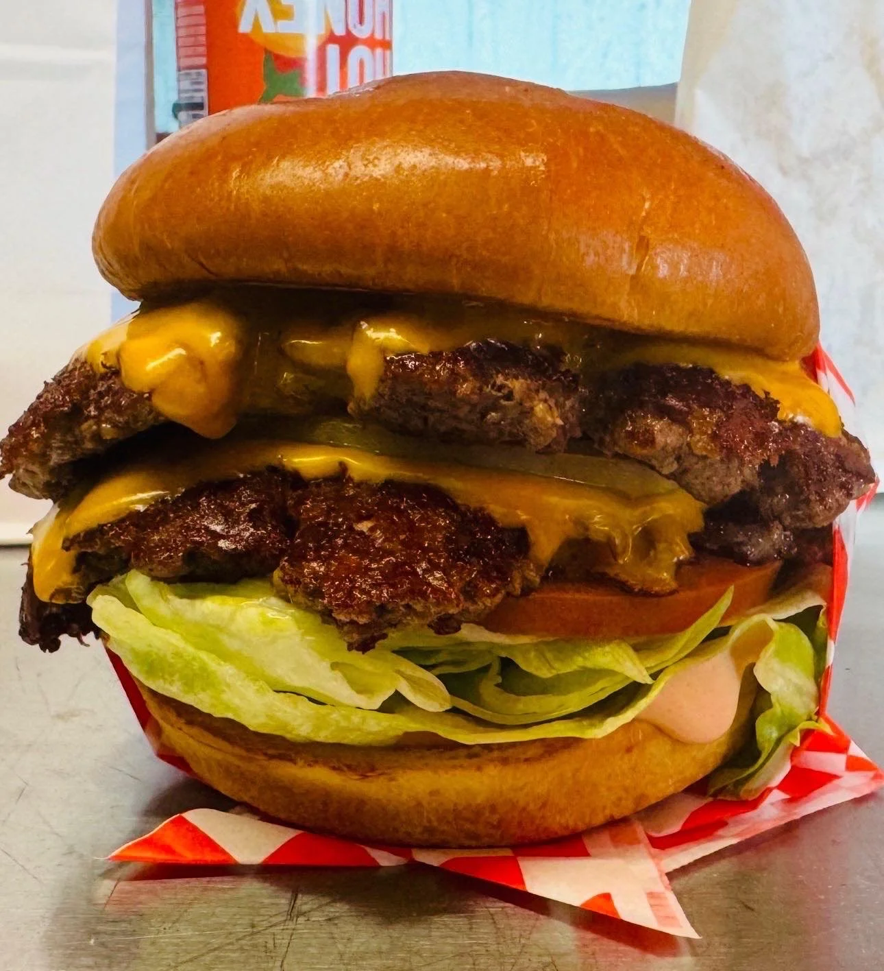 Two cheeseburgers with fries and three colorful beverages on a wooden table.