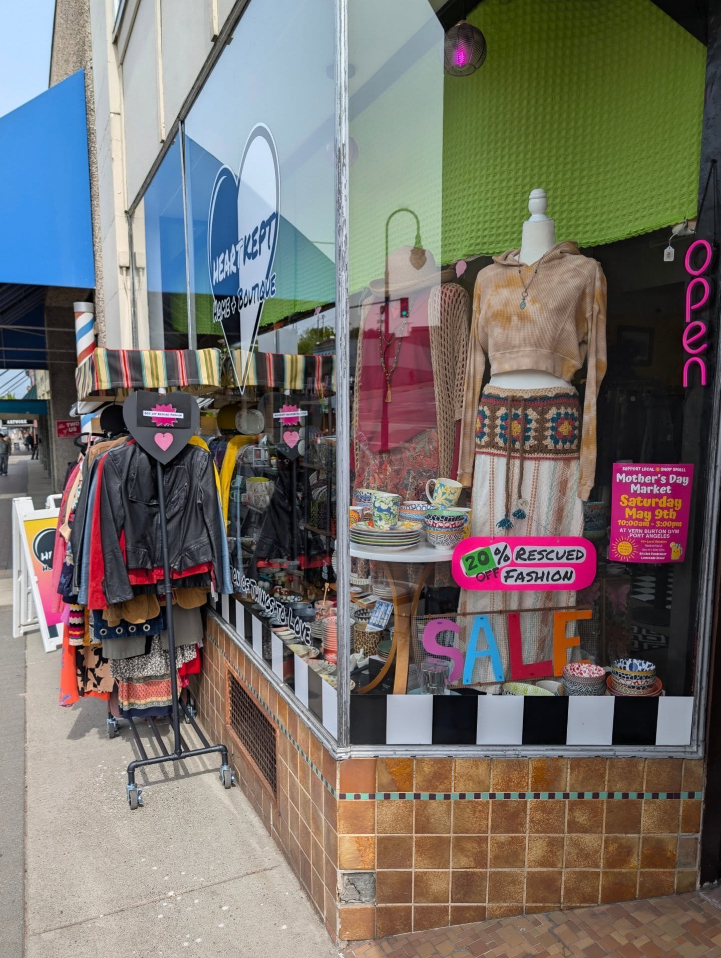 The outside of HeartKept Home + Boutique store in Port Angeles, WA, with a window display of different colorful outfits.