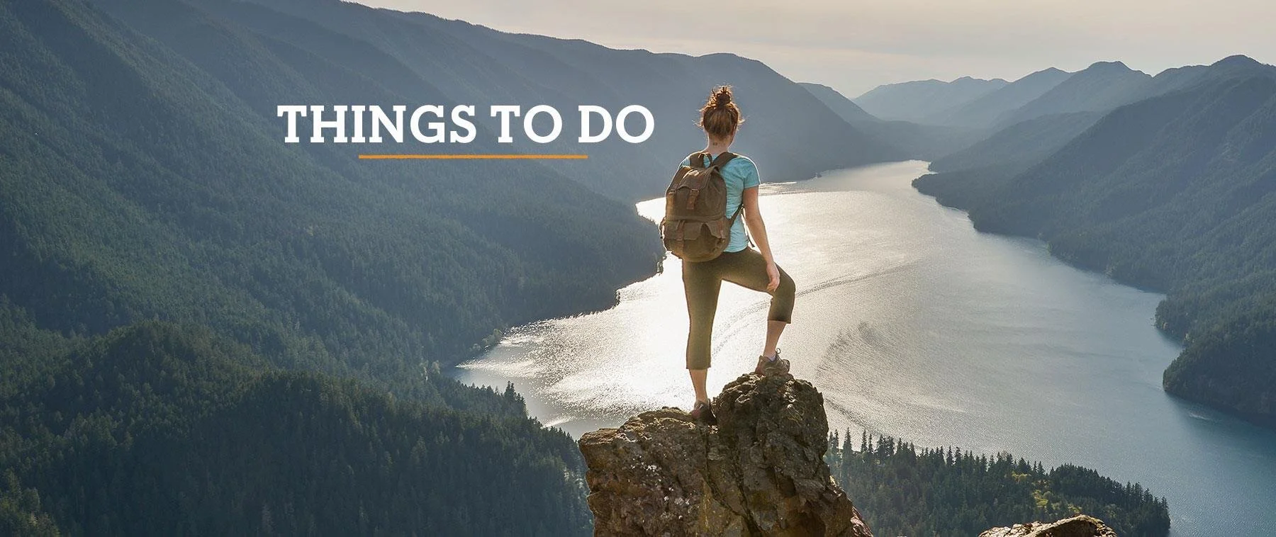 A person standing on a rocky cliff overlooking a river in a mountainous landscape, with the text 'Things to Do' overlaid.