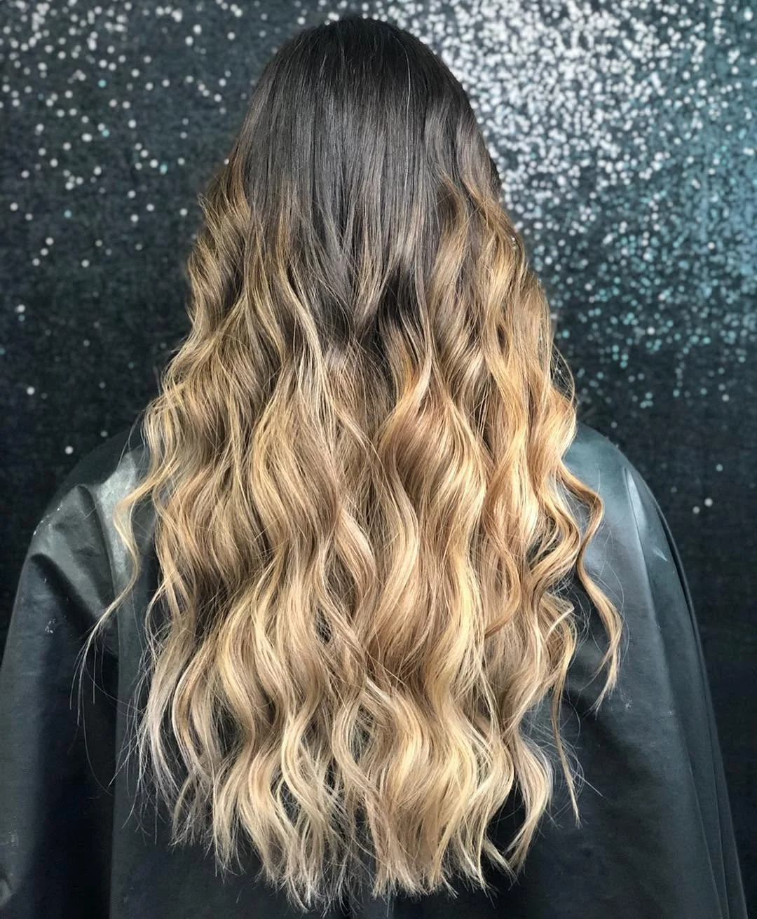 The back of a client's head to showcase their beautifully done hair curl & color.