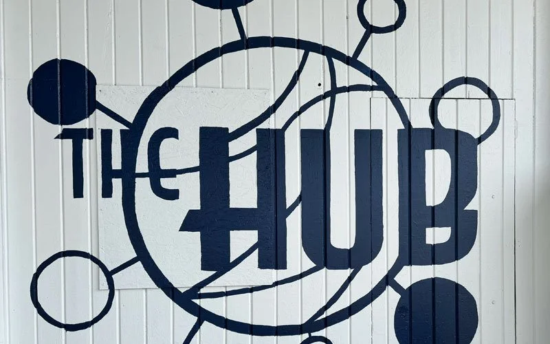 Wall with a large logo or sign that says 'THE HUB' in bold letters, featuring interconnected circles and lines, resembling a network or molecular structure.