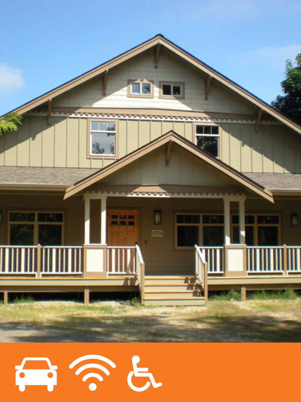 A residential house with a porch, stairs, and a gabled roof, under a blue sky with trees in the background.