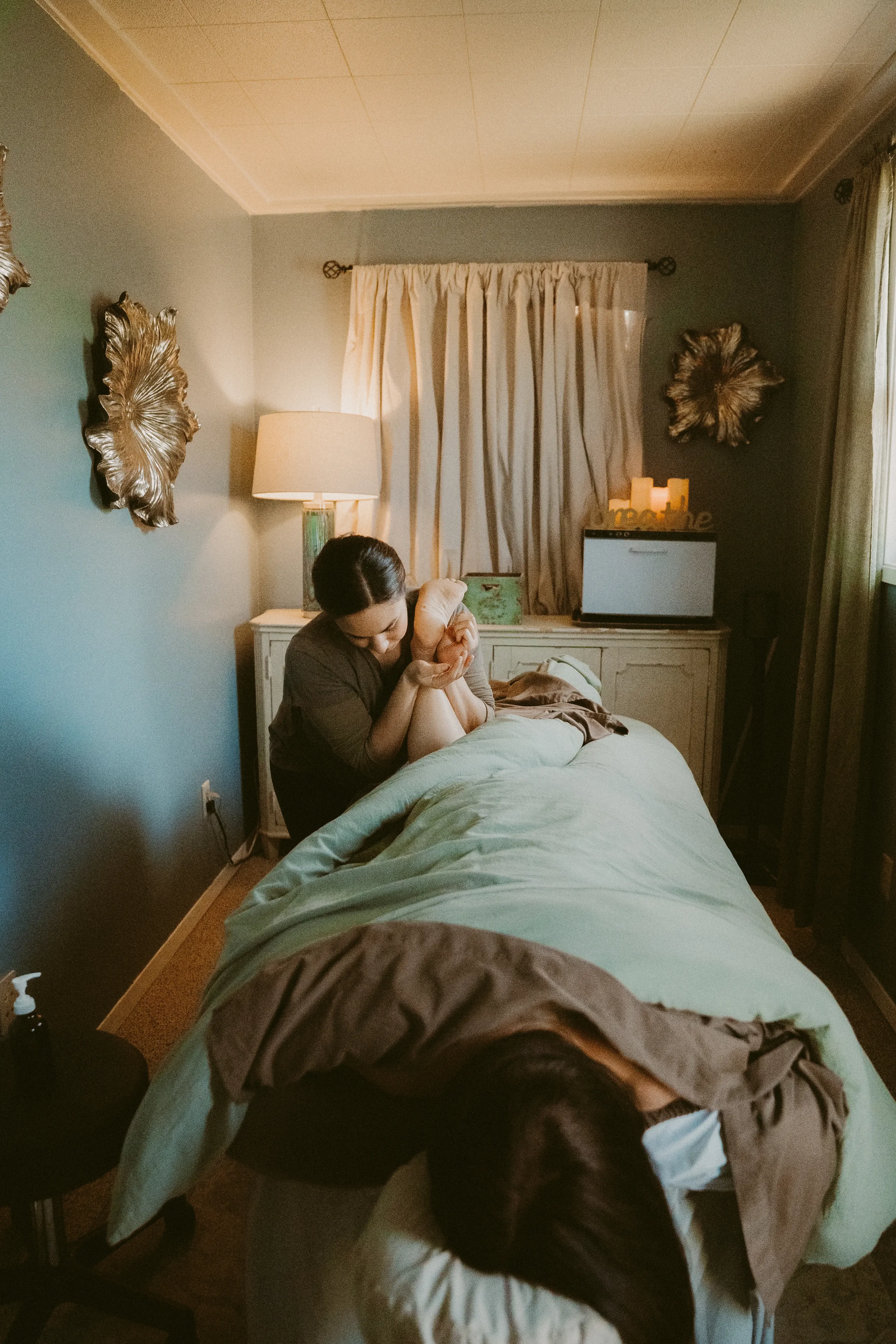 A person getting a massage on a massage table inside the Olympic Bodywork Professional studio, in a calm atmosphere with neutral decor on the walls.