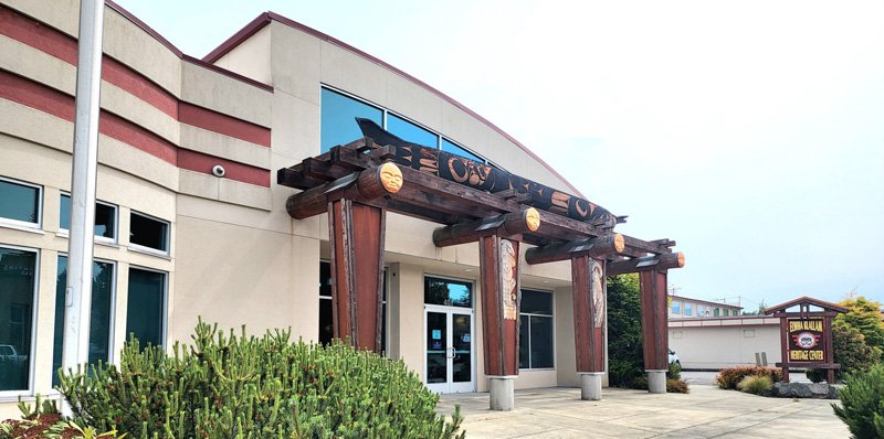 Exterior view of a building with a wooden archway and a sign indicating a business named "Sushi House."