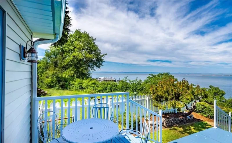 View from a balcony overlooking lush green trees, a large body of water, and a partly cloudy sky.
