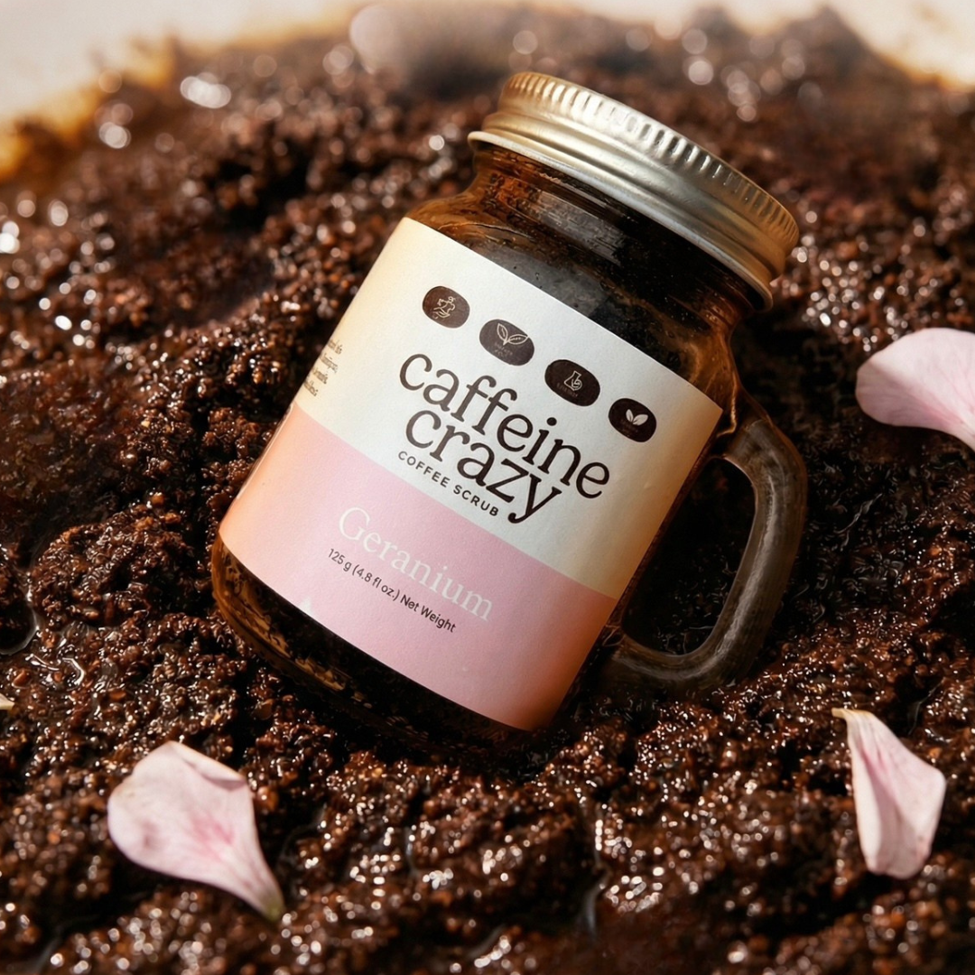 Geranium Coffee Scrub from Caffeine Crazy, laying in coffee scrub surrounded by geranium petals.