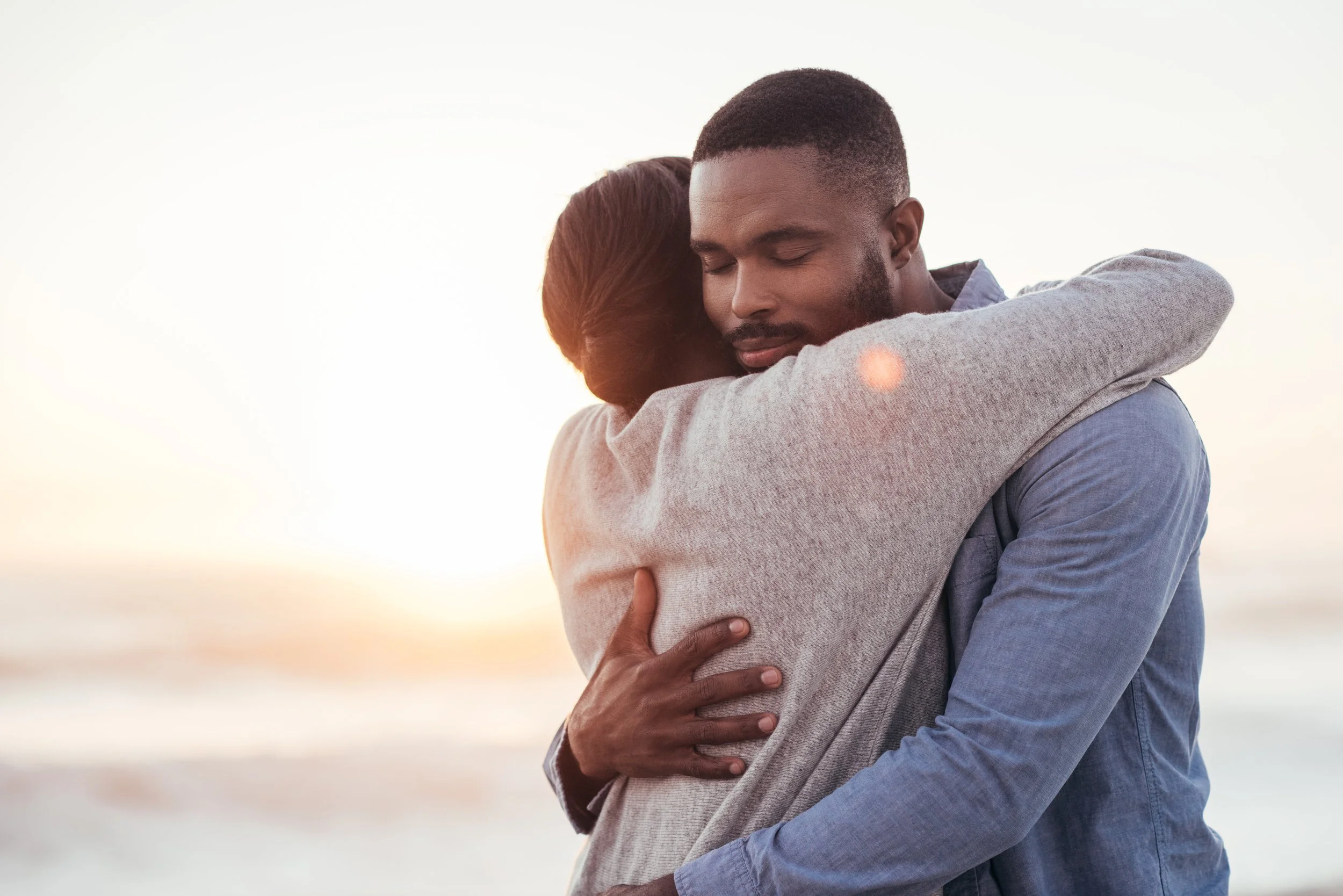 A couple embracing each other on a beach at sunset