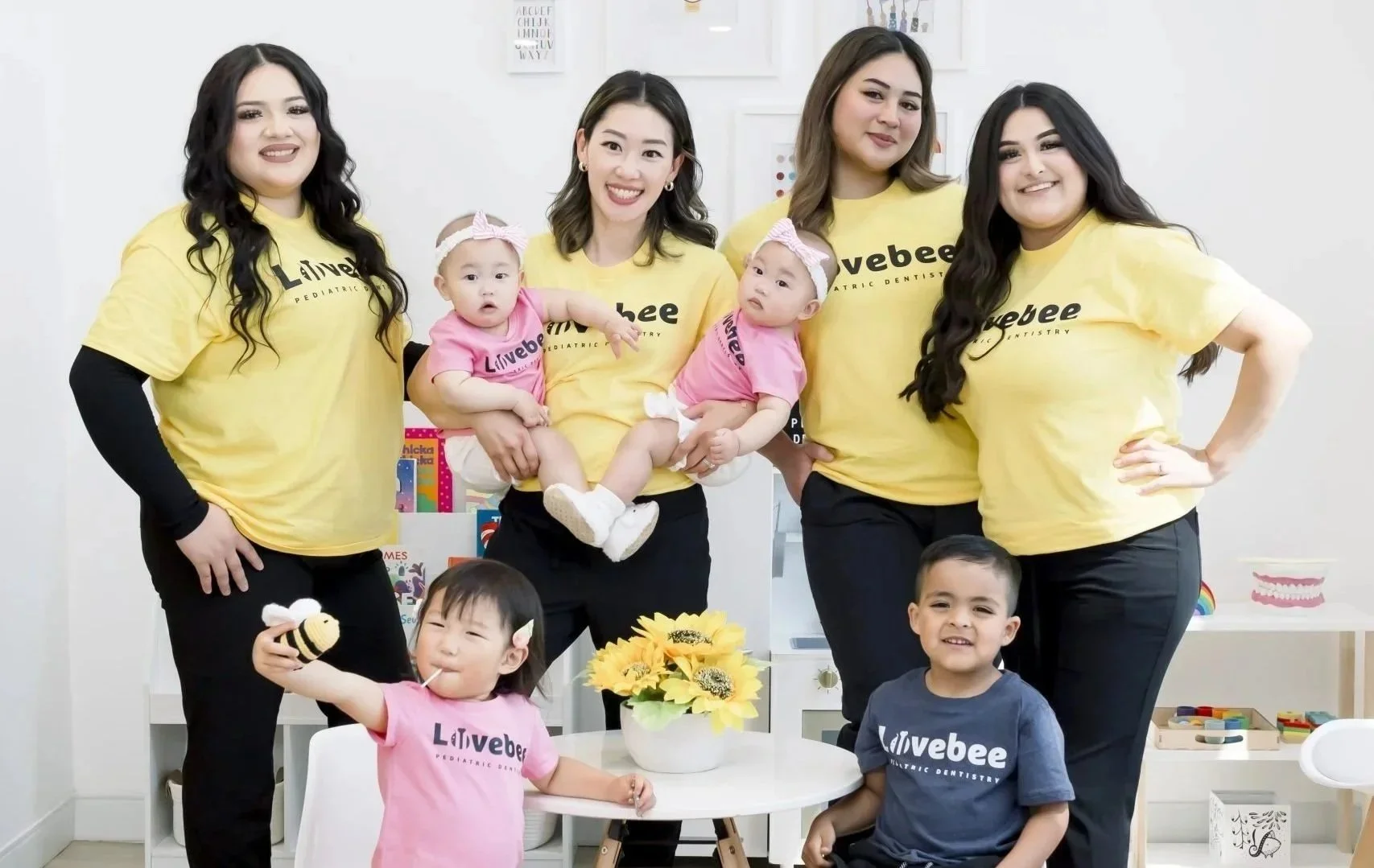 Lovebee team in a brightly decorated office with children's books and toys, celebrating at Lovebee pediatric dentistry office.