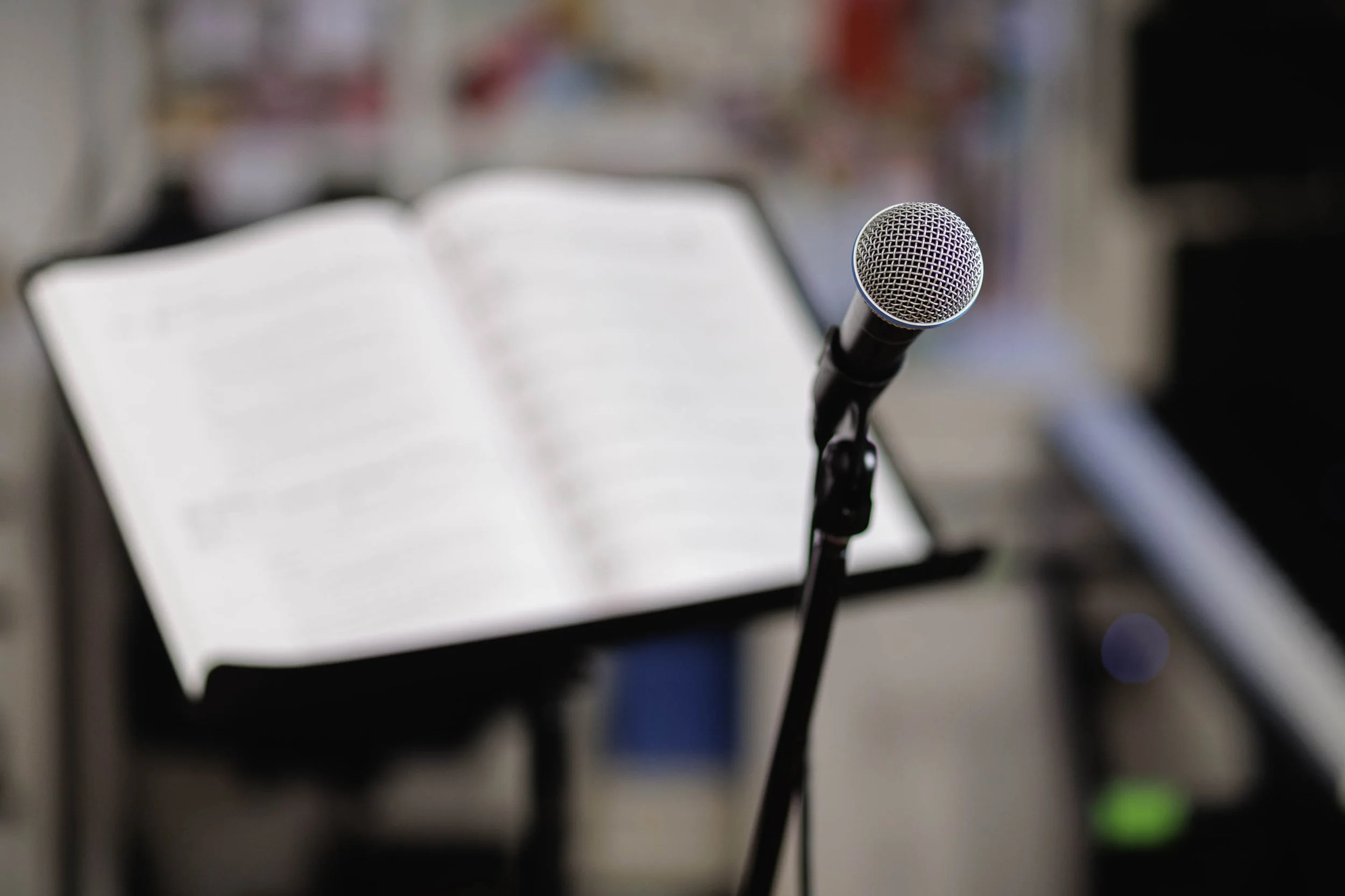 Microfono davanti a un libro aperto, sfocato sullo sfondo.