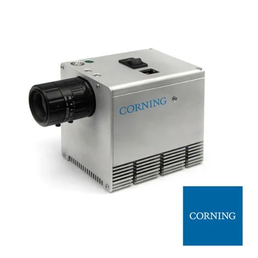 A laboratory or industrial device labeled CORNING with a black lens or attachment, metallic body, and vent slats at the bottom.